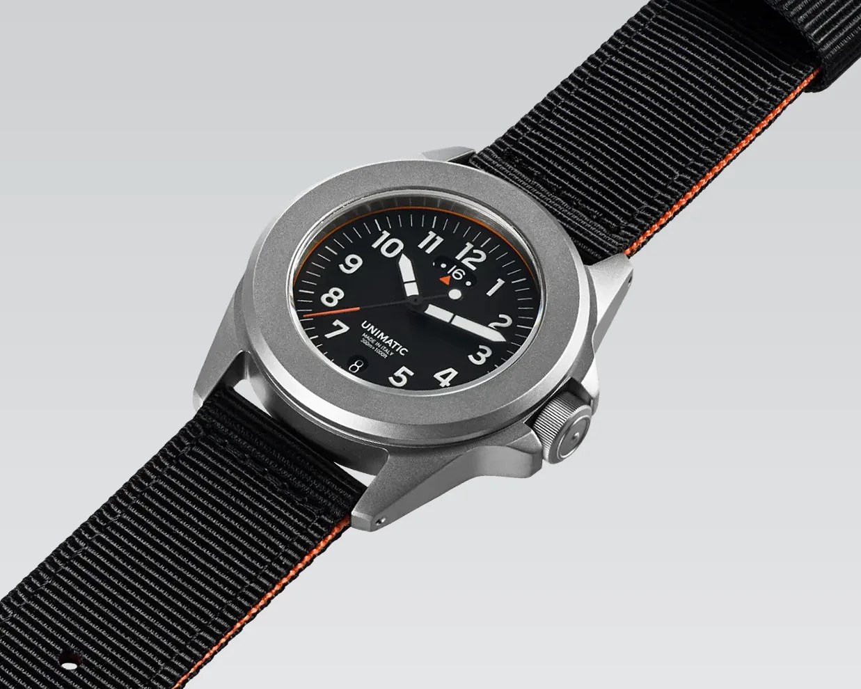 Silver stainless steel wristwatch with black dial, white numerals, and black fabric strap with orange edges.