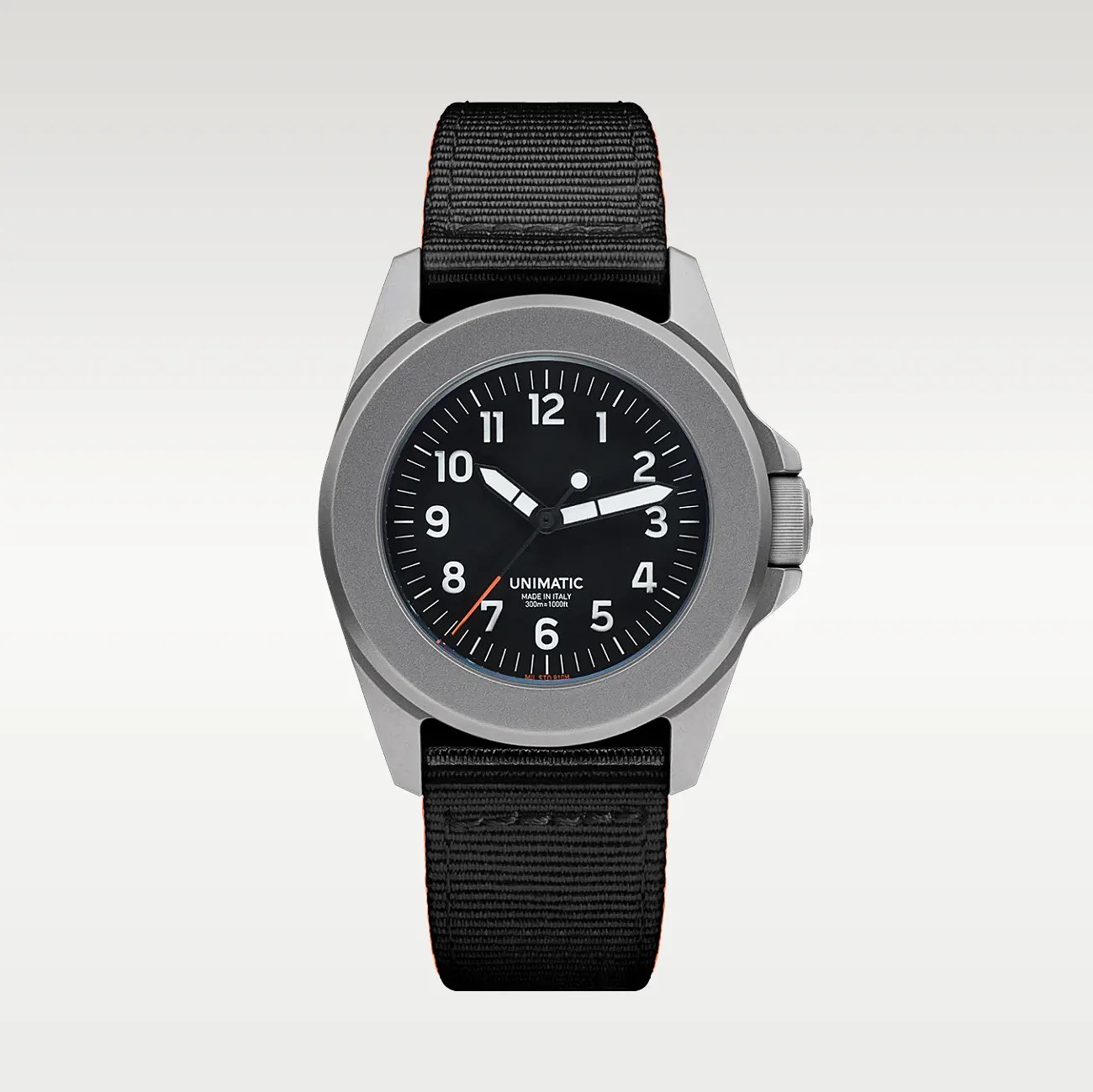 Watch with a matte silver case, black dial with white numerals, and black fabric strap.