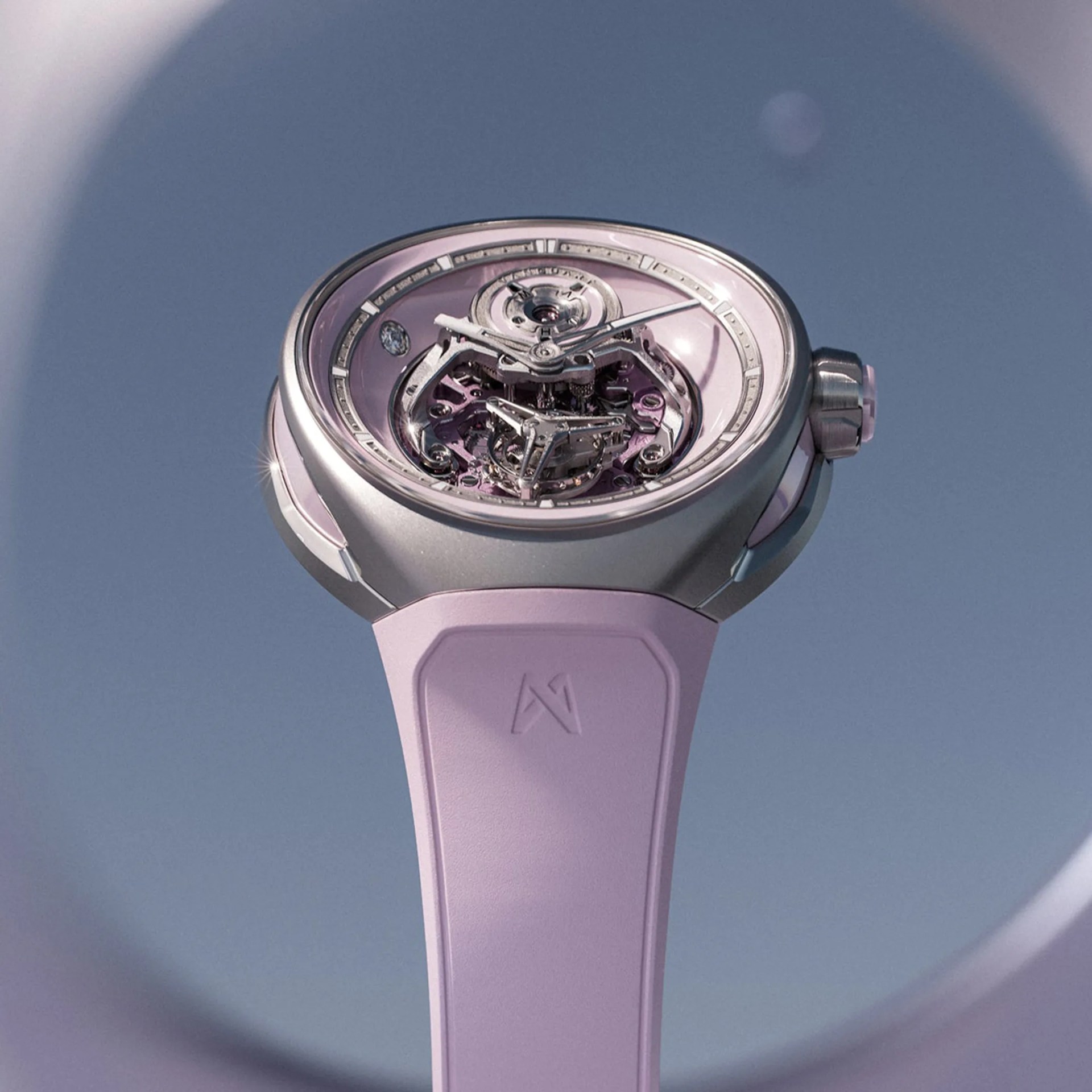 Close-up of a silver and pink mechanical wristwatch with a transparent dial and a pink strap.