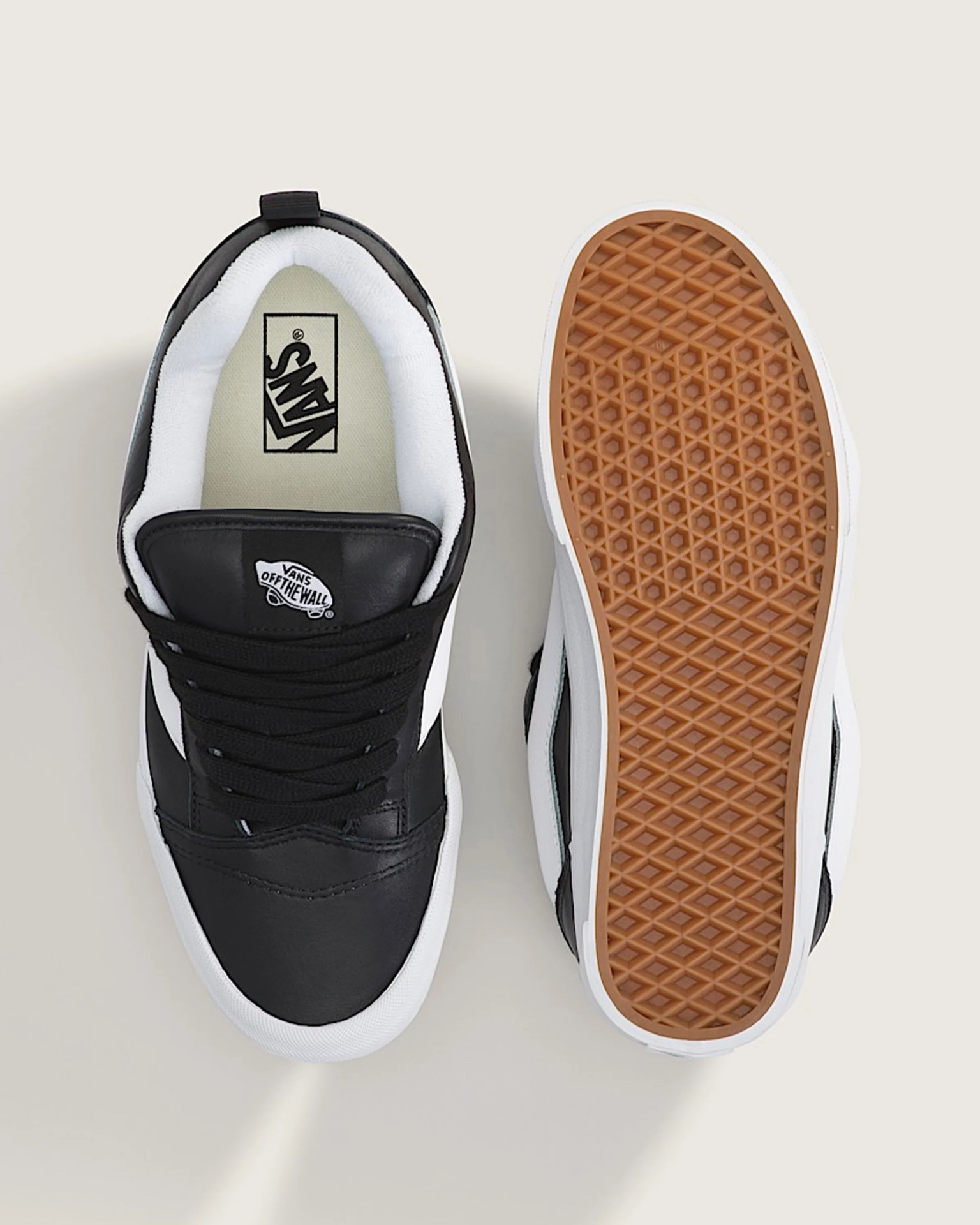 Pair of black and white Vans sneakers with white padded collars and gum rubber waffle soles.