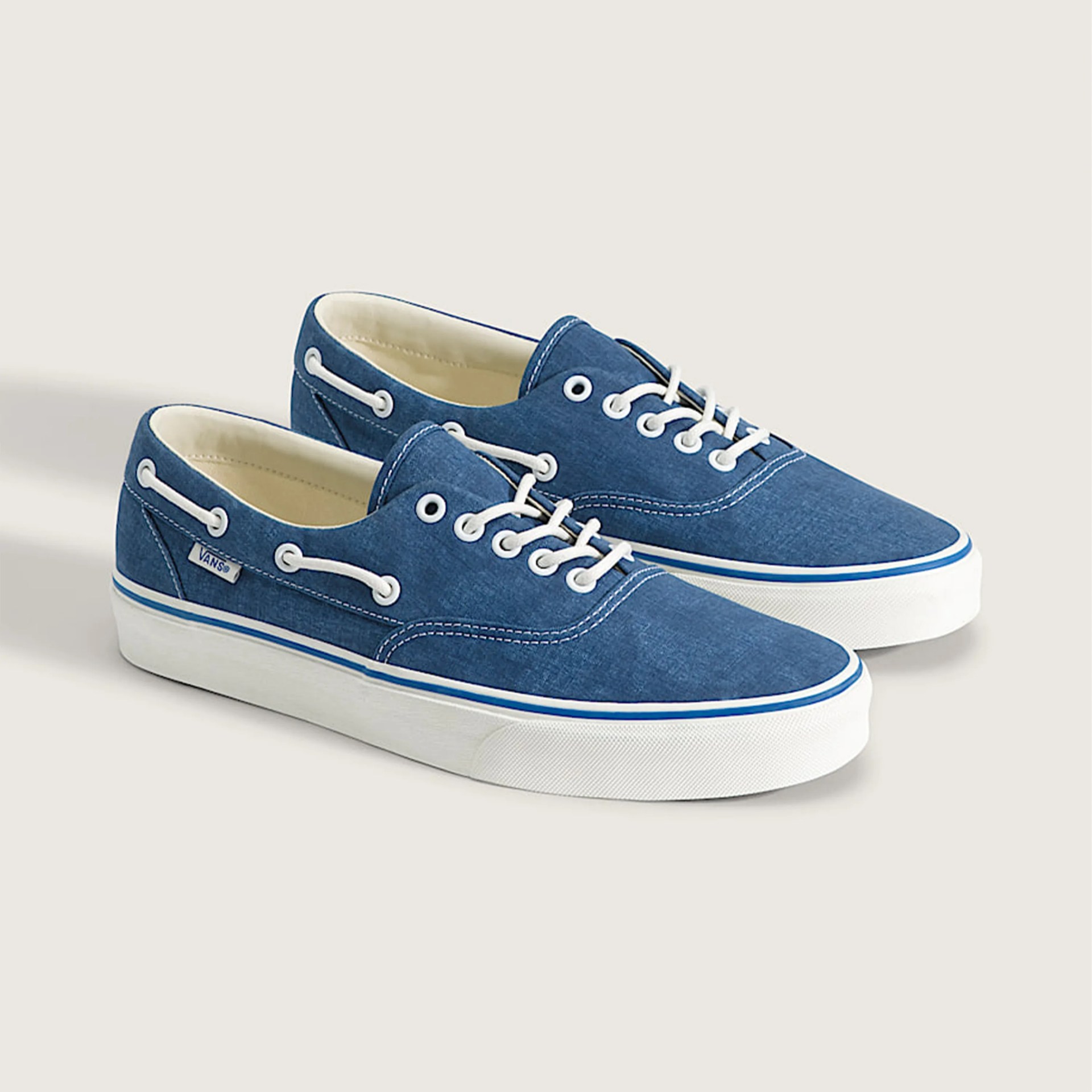 Pair of blue Vans boat shoes with white laces and white rubber soles on a light background.
