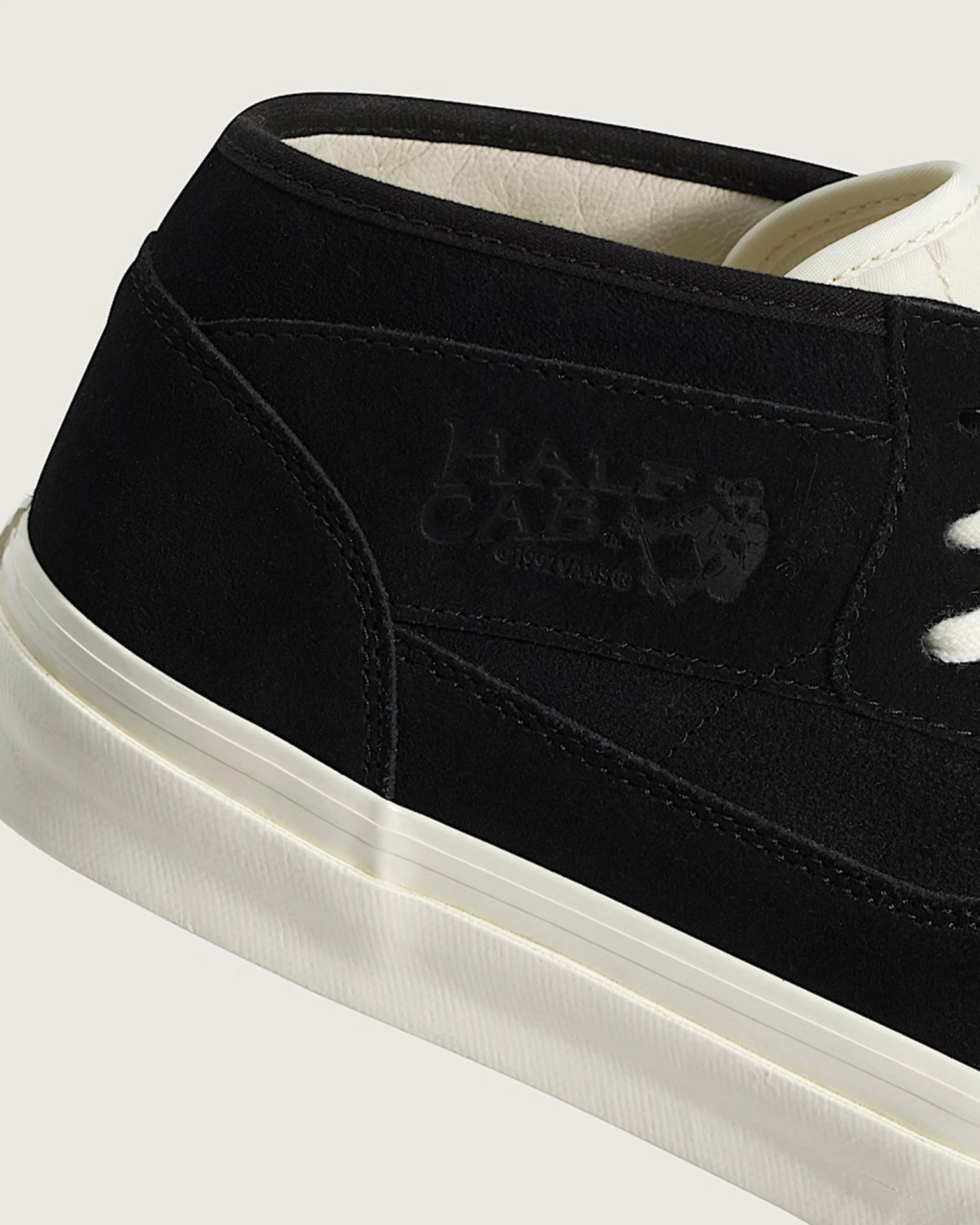Close-up of black suede Vans Half Cab sneaker with white sole and cream inner lining.