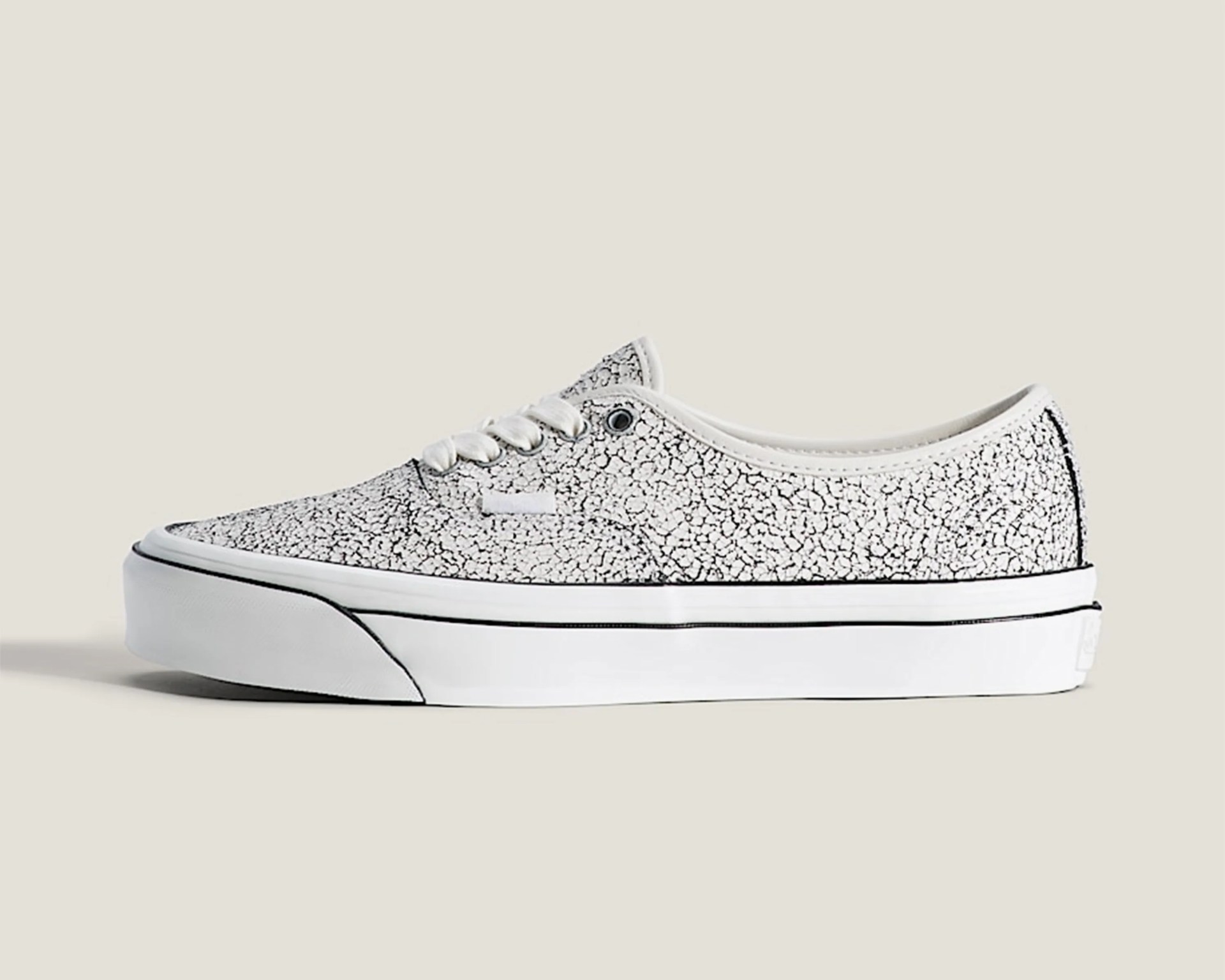White low-top sneaker with black crackle pattern and white rubber sole with black stripe.