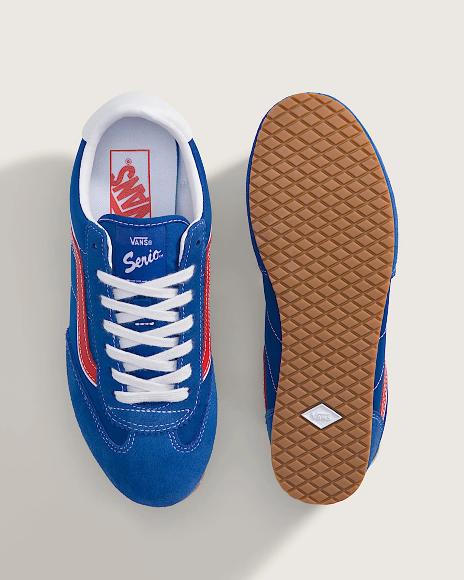 Pair of blue Vans Serio sneakers with white laces, red stripe, and gum rubber waffle sole.