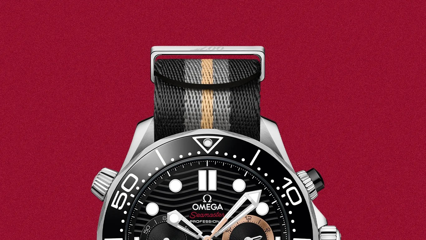 Black Omega Seamaster Professional watch with silver case and black, gray, and beige striped fabric strap on a red background.