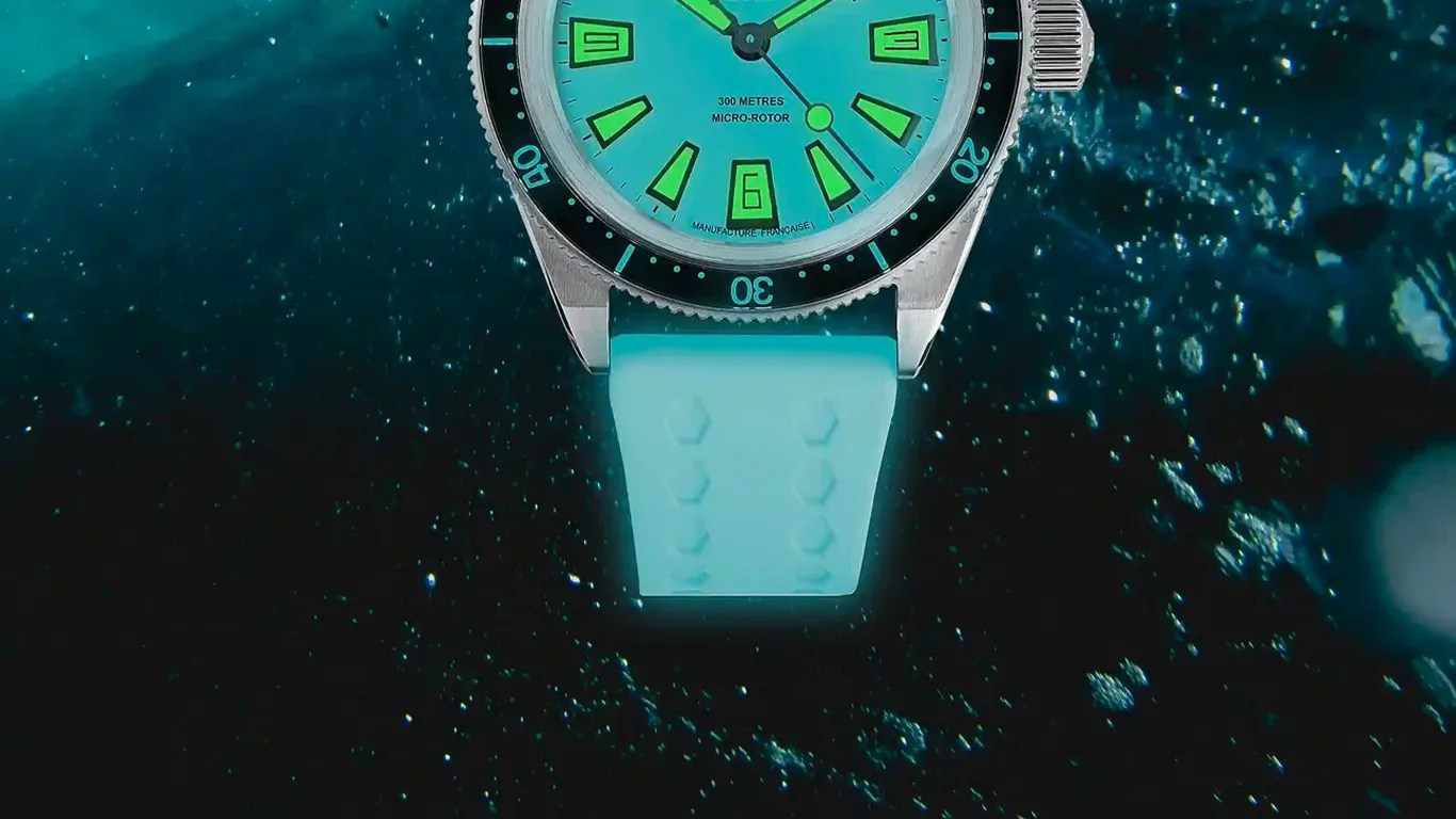 Close-up of a turquoise dive watch with green luminescent markers and a matching silicone strap underwater.