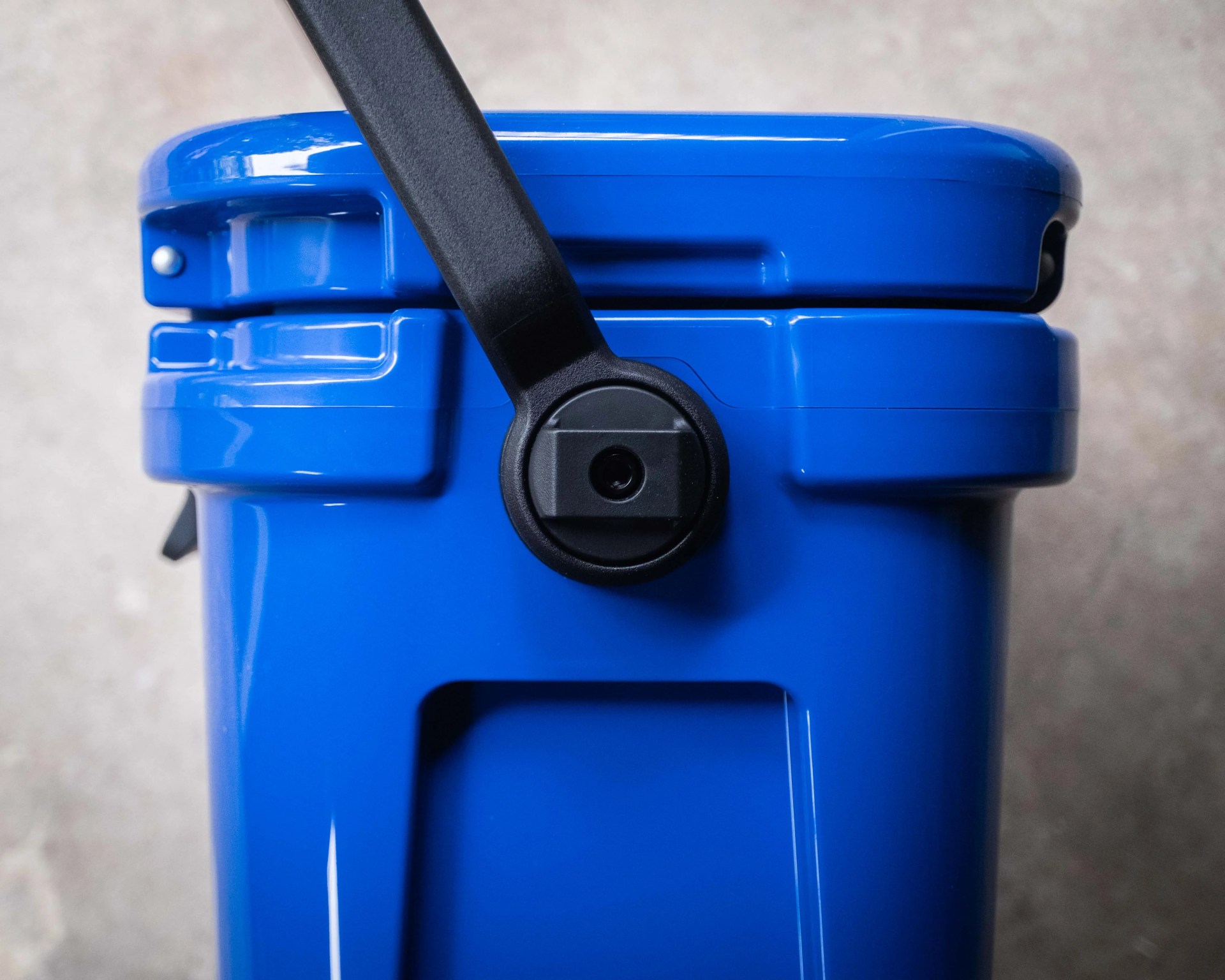 Close-up of a blue plastic container with a black handle attached on top.