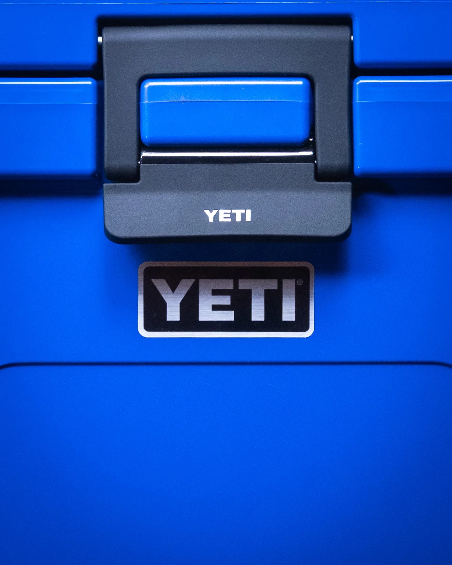 Close-up of a blue YETI cooler latch with the YETI logo below it.