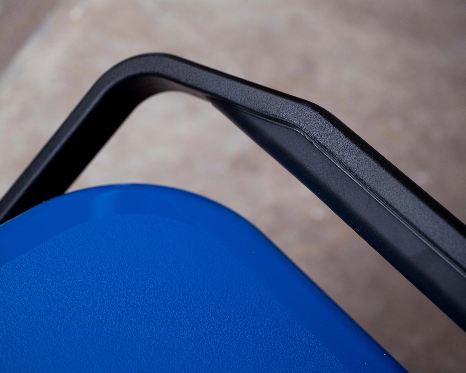 Close-up of a black plastic handle attached to a blue textured surface.