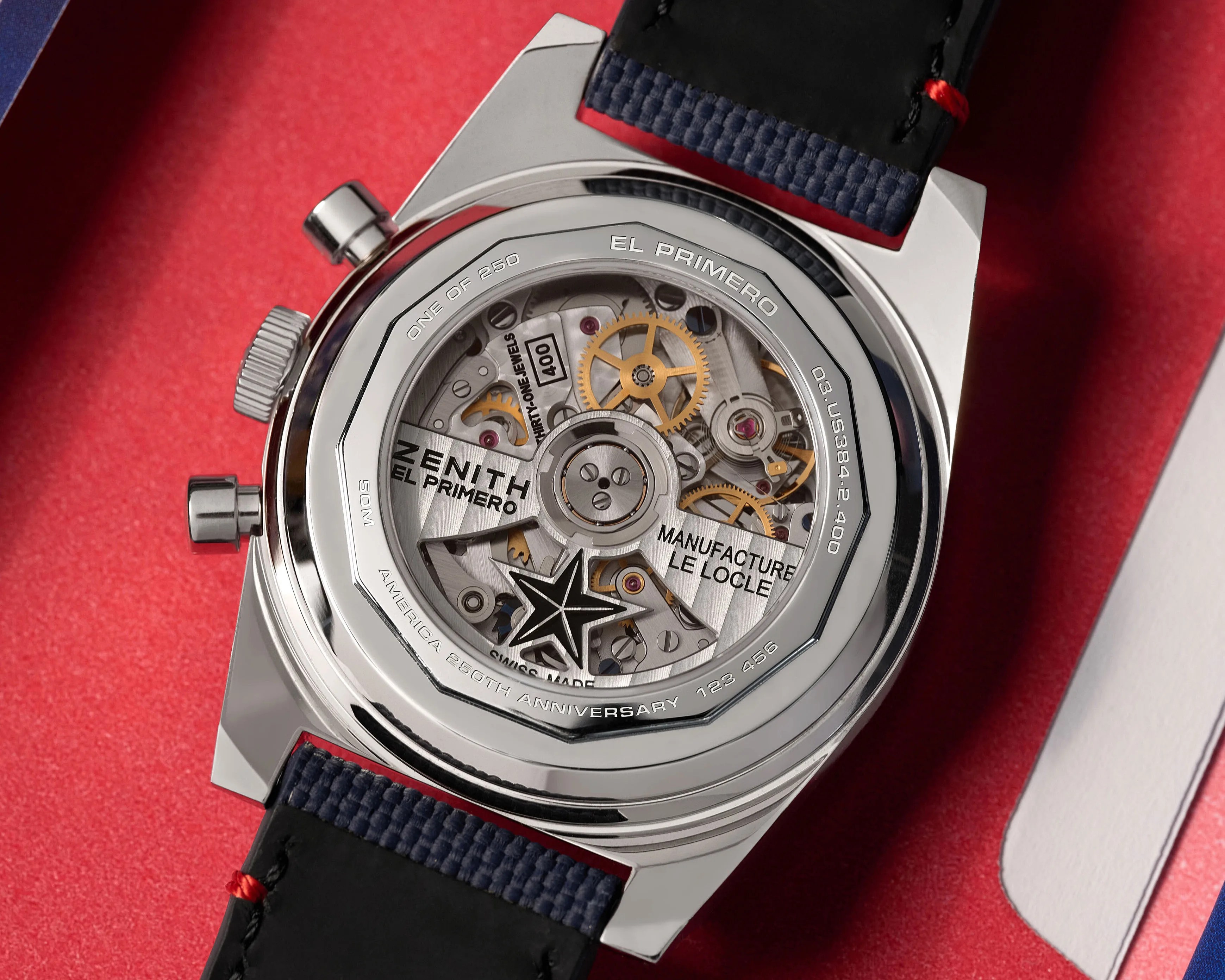 Close-up of the back of a Zenith El Primero watch showing its intricate mechanical movement and blue fabric strap.
