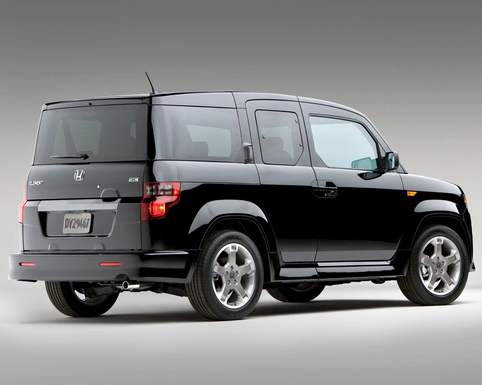 Black Honda Element SUV rear side view with tinted windows and silver alloy wheels on a gray background.