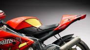 Close-up of red Aprilia motorcycle seat and rear section with "Spain's No 1" decal and silver exhaust pipe.