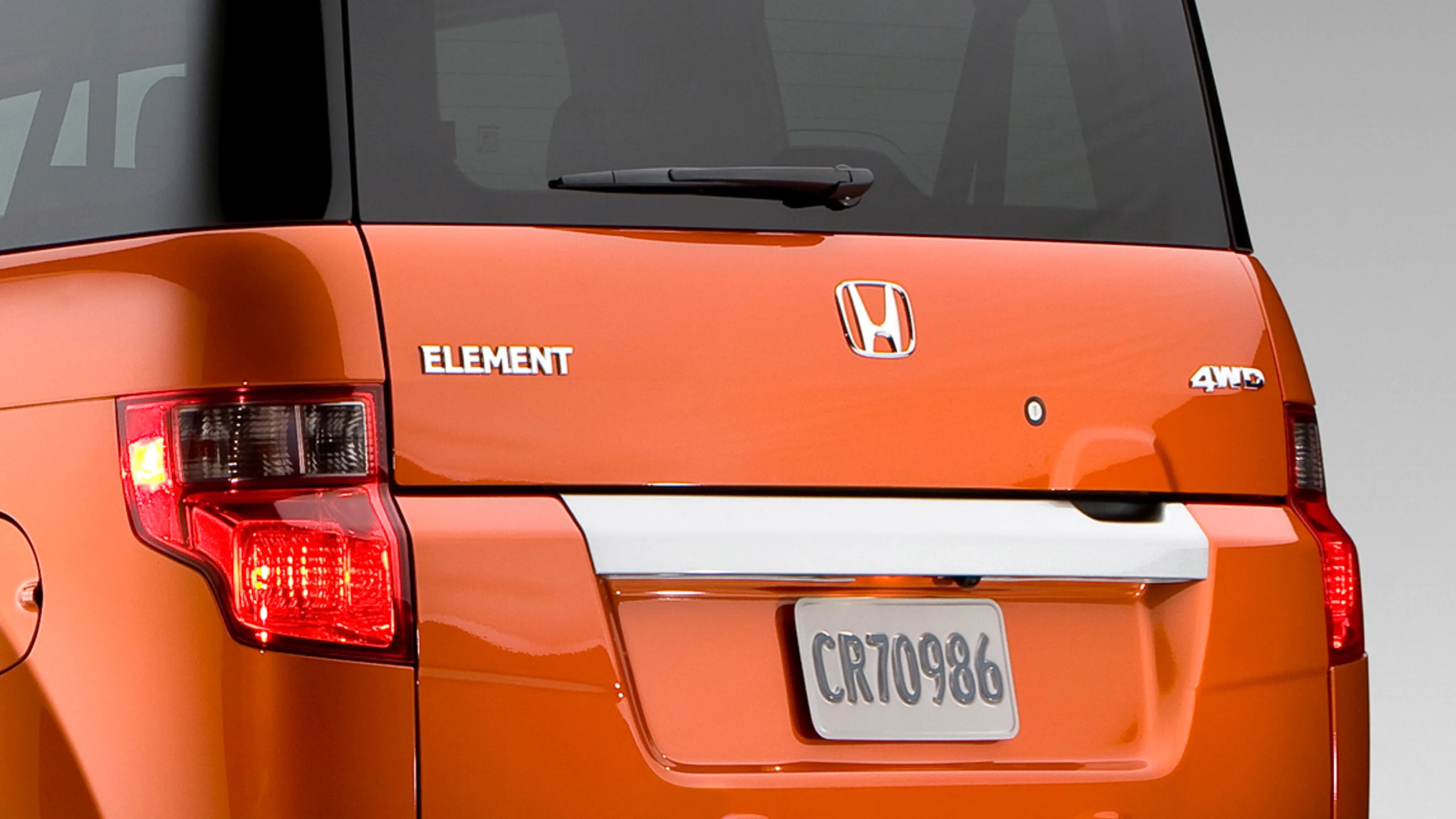 Rear view of an orange Honda Element 4WD with visible taillights and license plate CR70986.