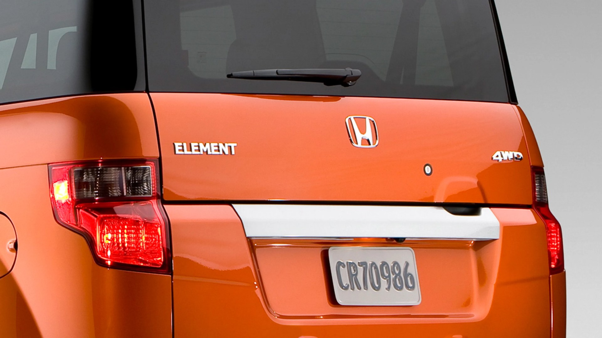 Rear view of an orange Honda Element 4WD with visible taillights and license plate CR70986.