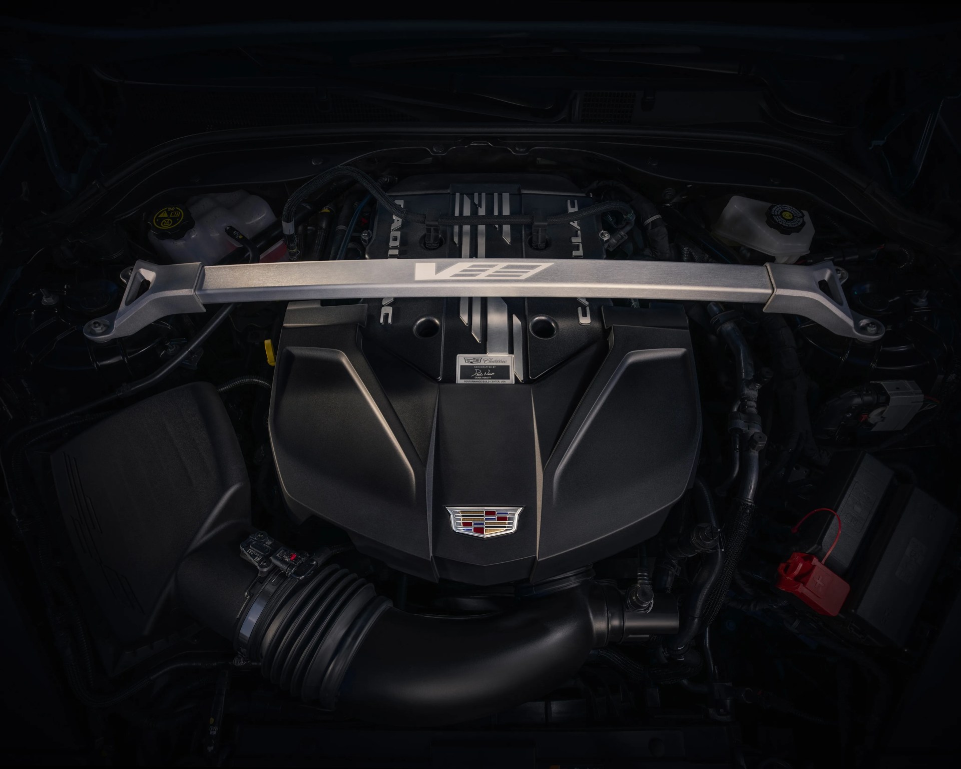 Cadillac V-series engine with black cover and silver strut bar across the top.
