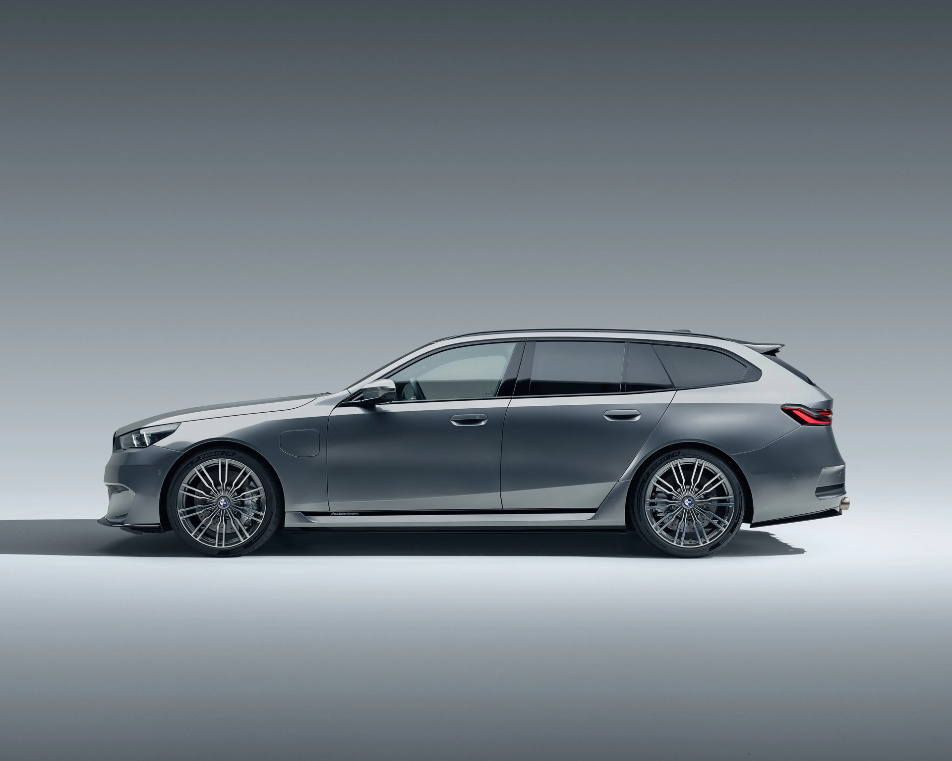 Side view of a sleek gray station wagon with tinted windows and multi-spoke alloy wheels on a plain background.
