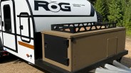 White ROG Adventure Series camper trailer with a tan and black storage box attached to the front.