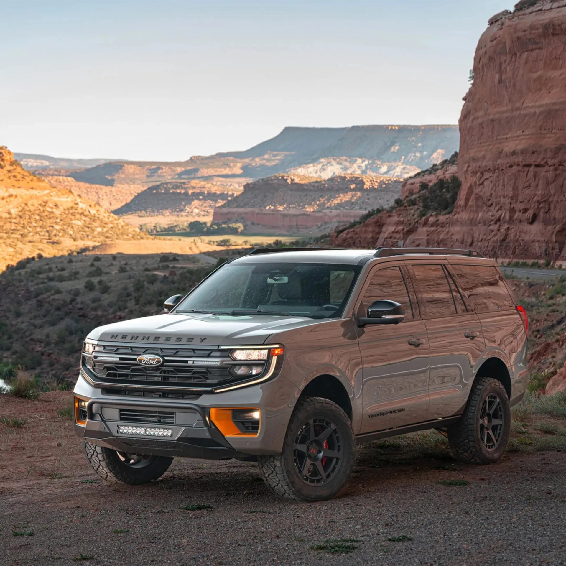 Silver Ford SUV with Hennessey branding parked on a dirt road near red rock cliffs.