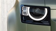 Close-up of a rectangular car headlight with LED ring and two square LED elements on a matte green vehicle.