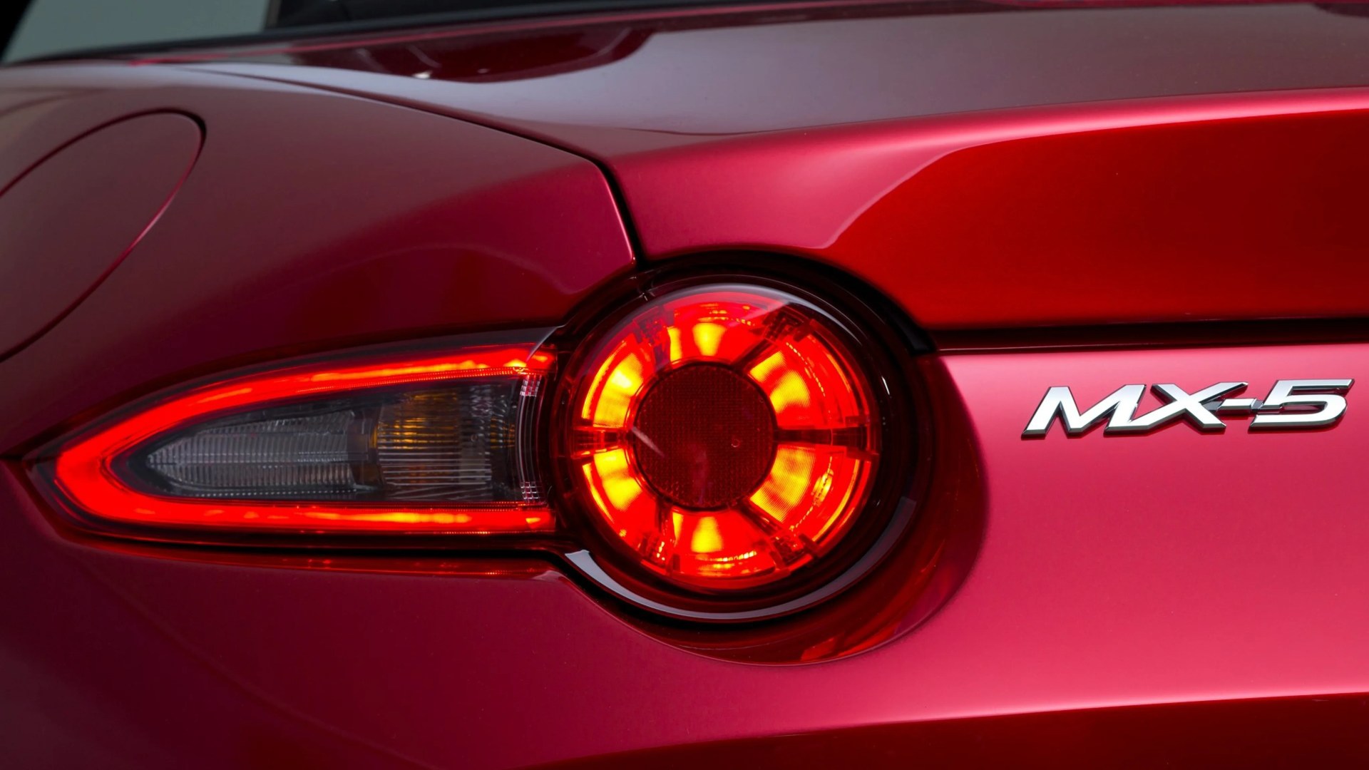 Close-up of a red Mazda MX-5 rear taillight with illuminated circular brake light.