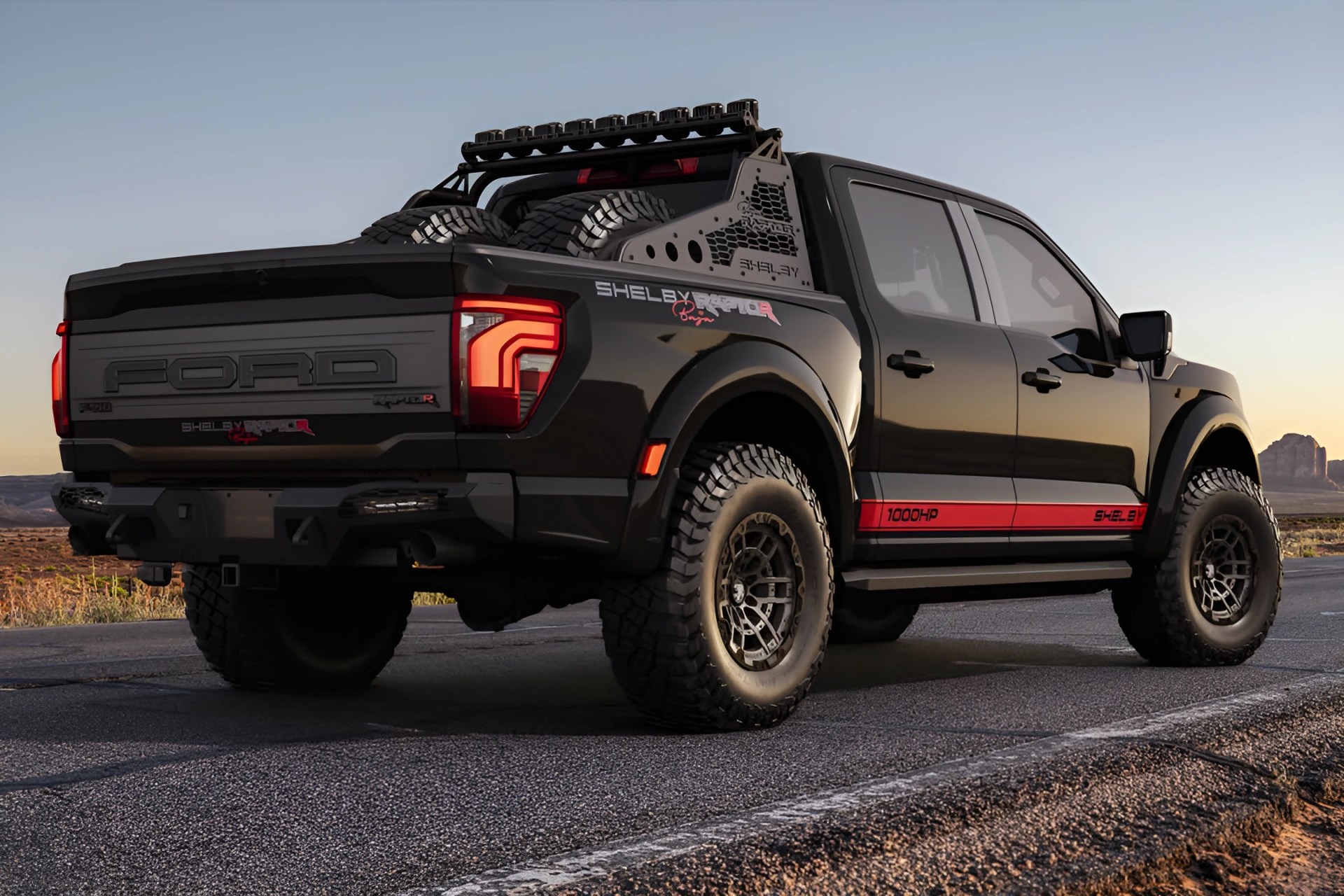 Black Shelby Ford Raptor pickup truck with off-road tires and spare tires in the bed at sunset.