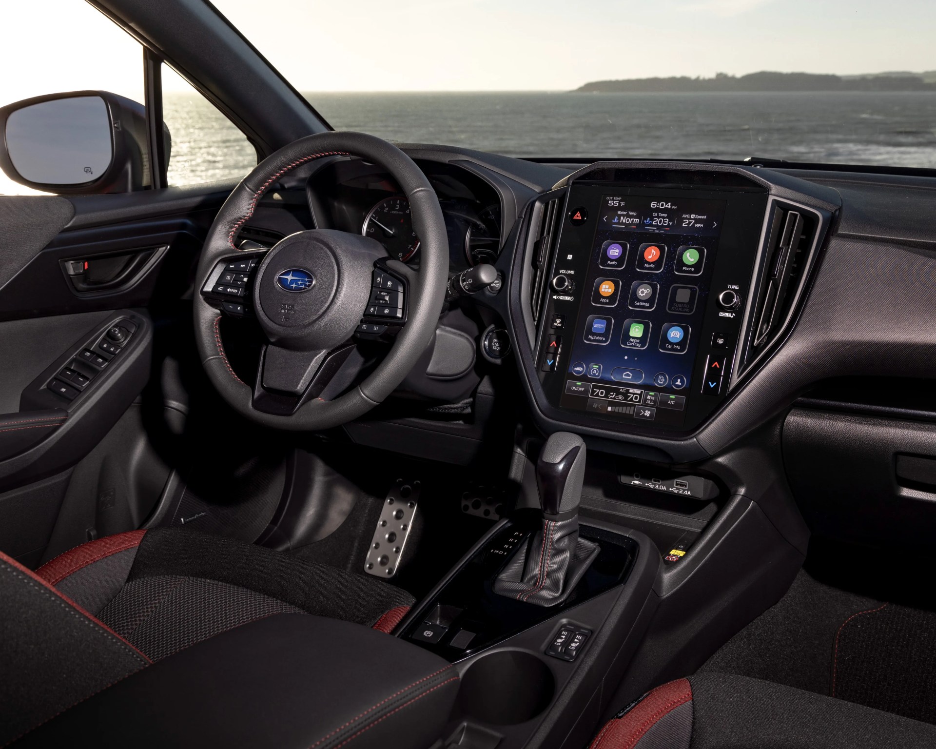 Black and red fabric car seats with a black leather steering wheel featuring red stitching and a large touchscreen infotainment system.
