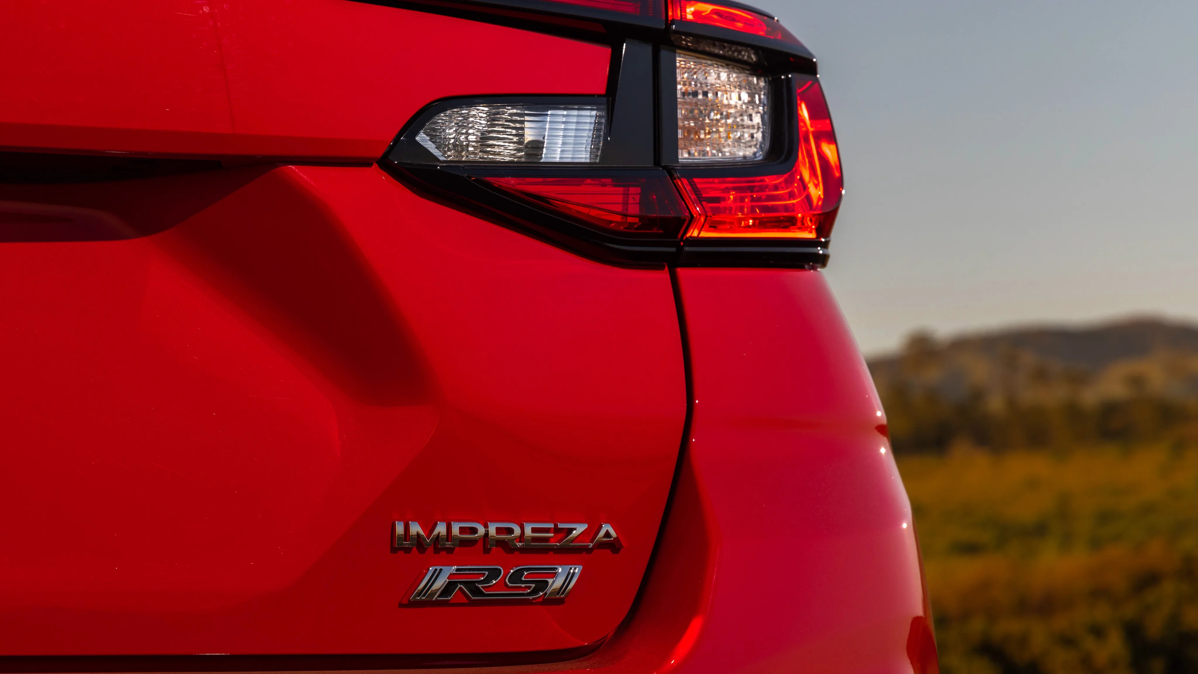 Rear section of a red Subaru Impreza RS with visible taillight and badges.