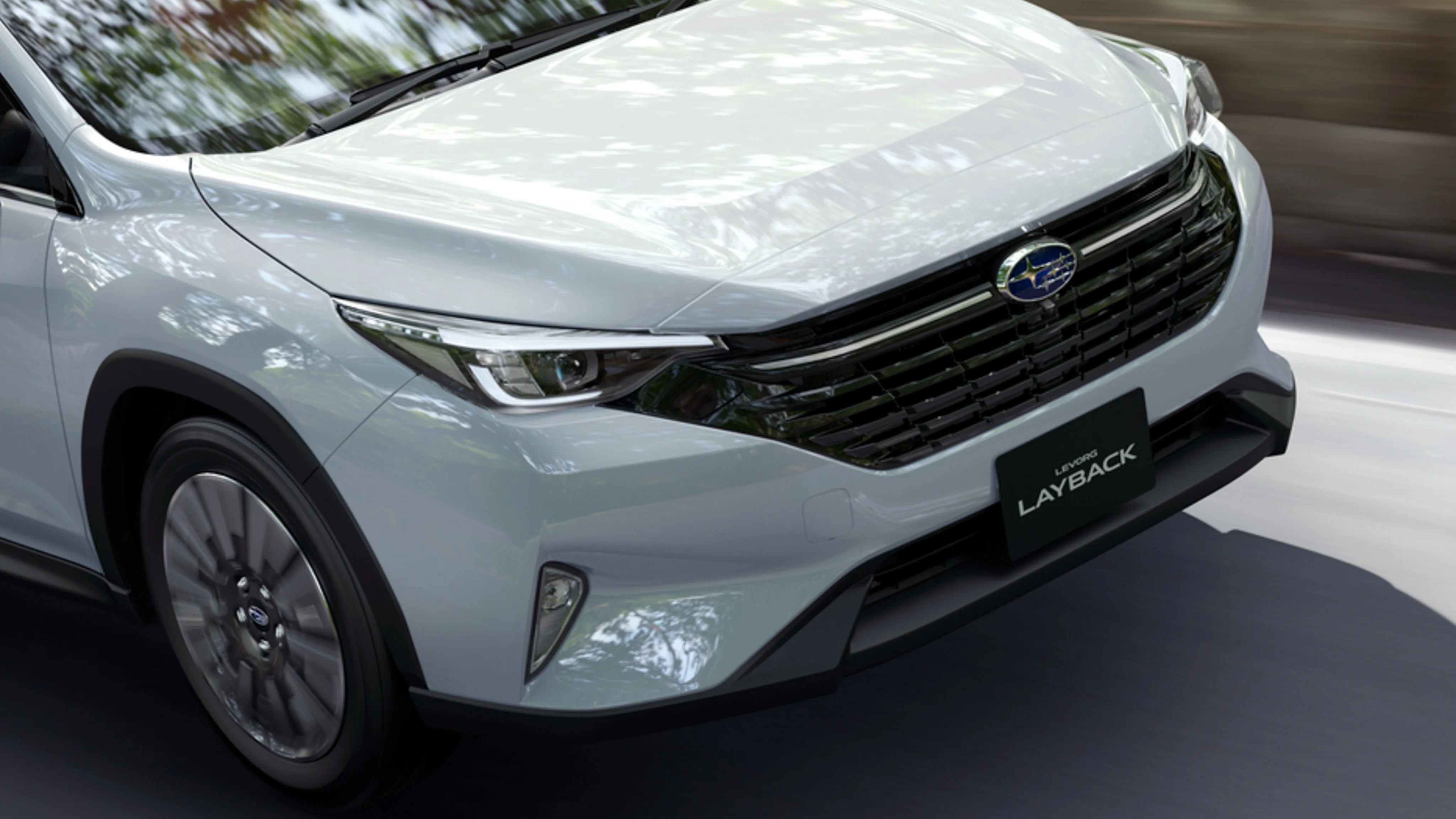 Front view of a silver Subaru Layback with a black grille and LED headlights on a road.
