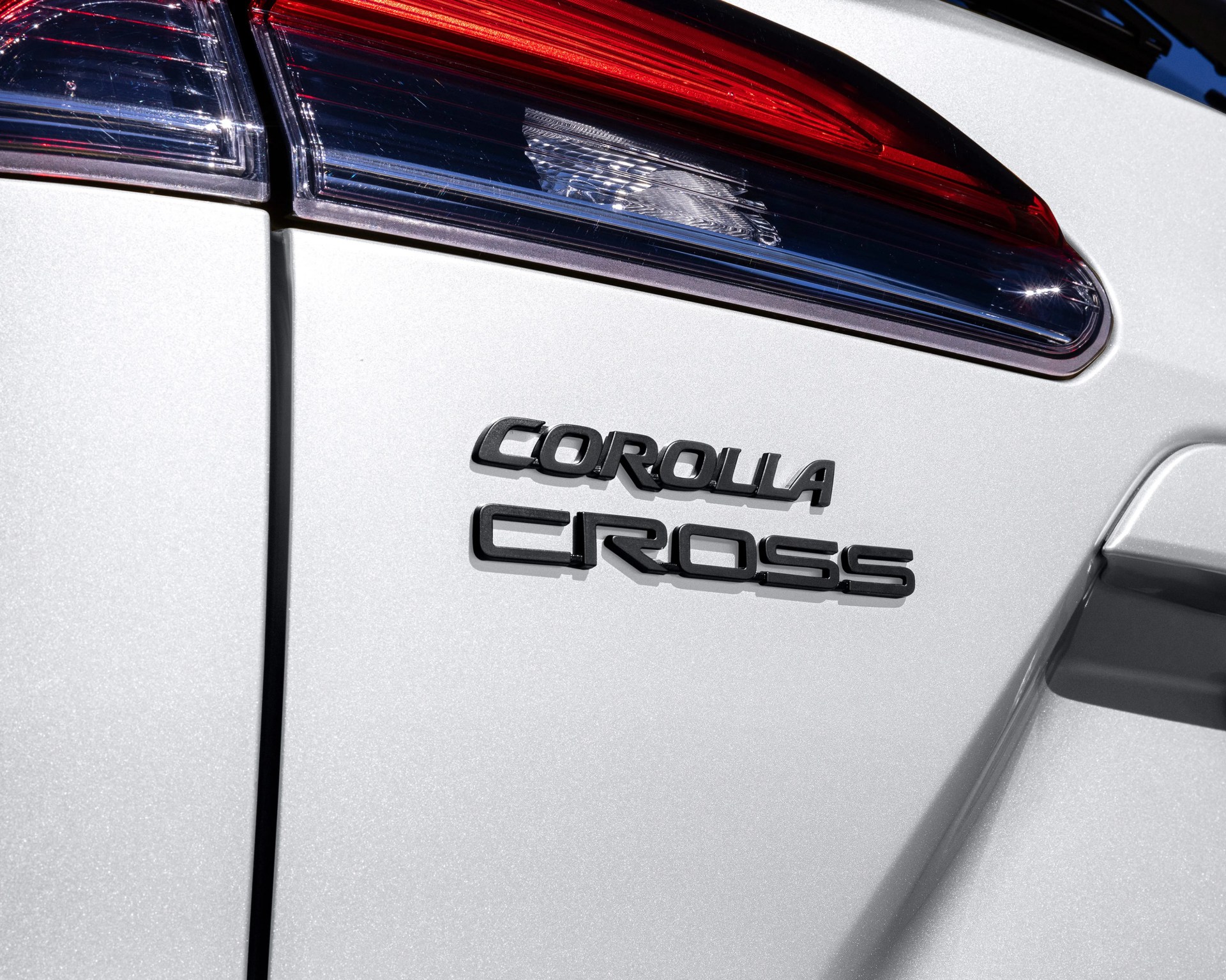 Close-up of white Toyota Corolla Cross rear with black model name badge and part of the taillight.
