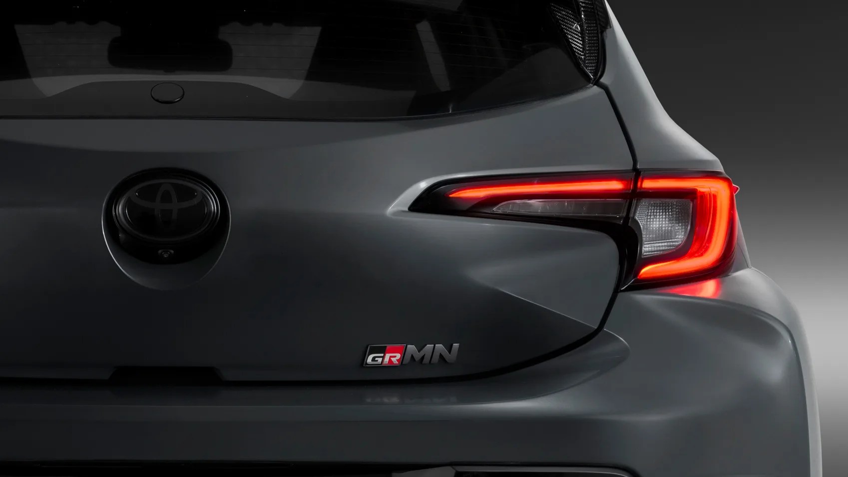 Rear view of a gray Toyota GRMN hatchback showing the illuminated right taillight and GRMN badge.