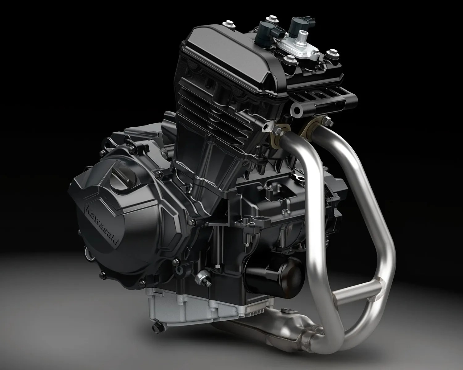 Black and silver Kawasaki motorcycle engine with dual exhaust pipes on a gray surface.