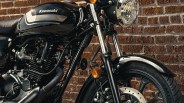Black Kawasaki motorcycle with silver accents parked in front of a brick wall.