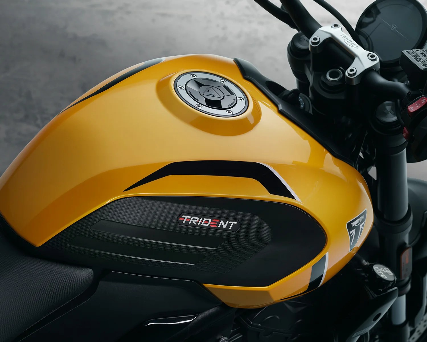 Yellow Triumph Trident motorcycle fuel tank with black accents and silver fuel cap.