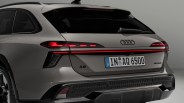 Rear view of a gray Audi A6 allroad with illuminated taillights and a European license plate.