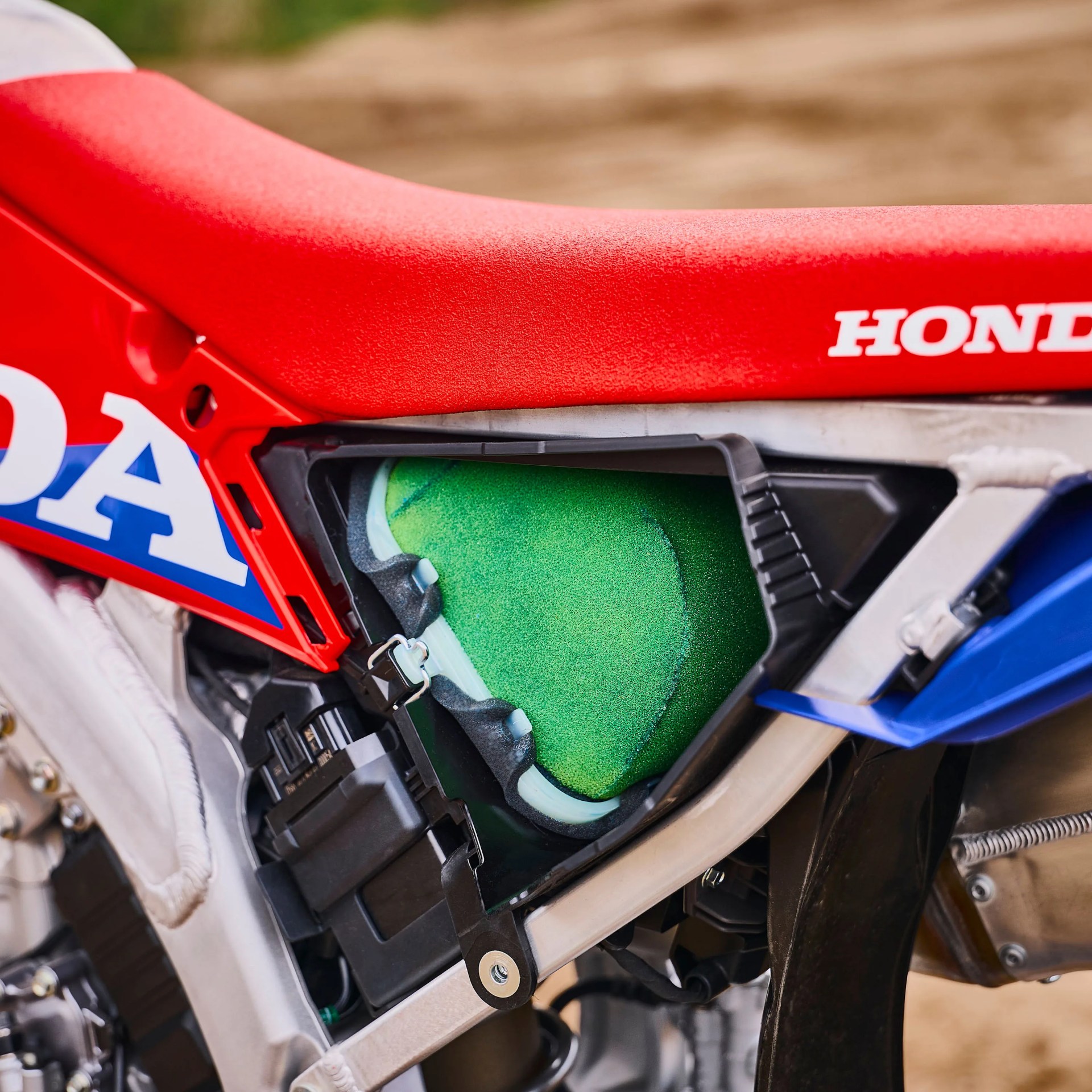 Close-up of a red Honda motorcycle seat and exposed green air filter inside the frame.