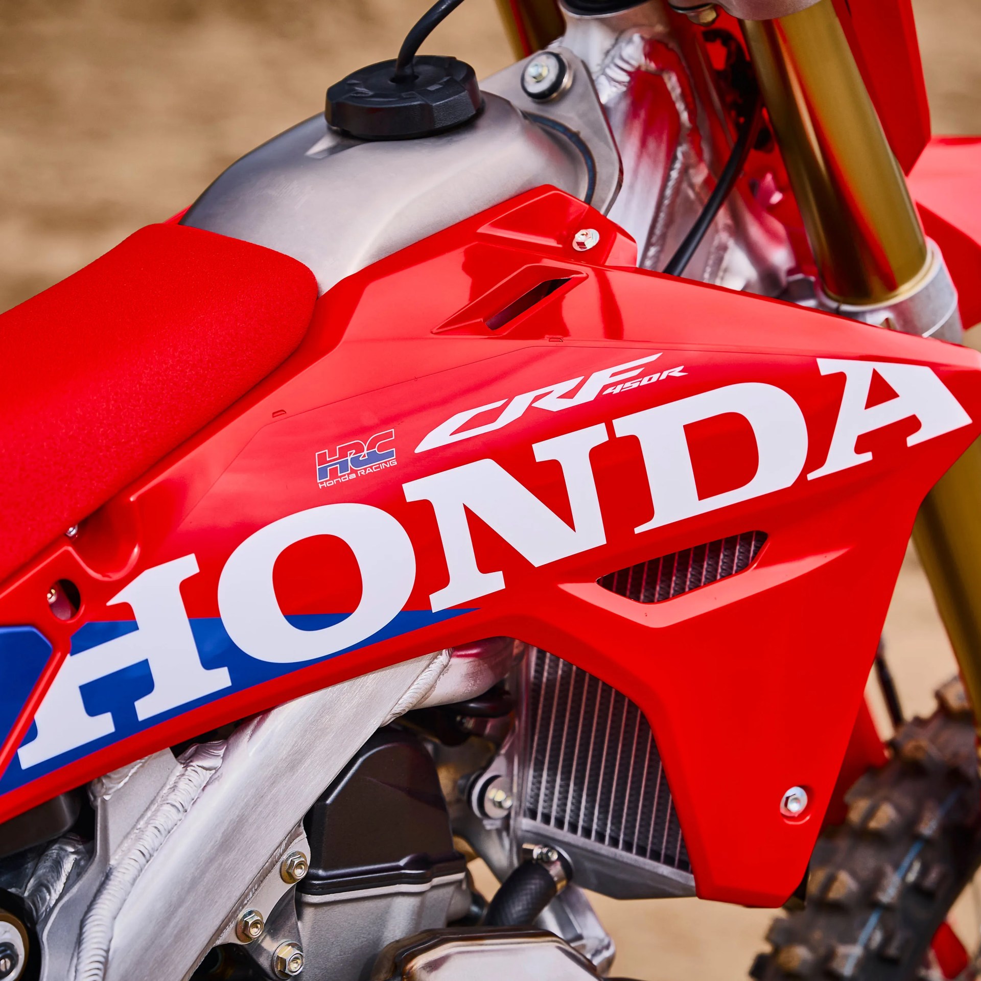 Close-up of red Honda CRF 450R dirt bike fuel tank, seat, and engine components.
