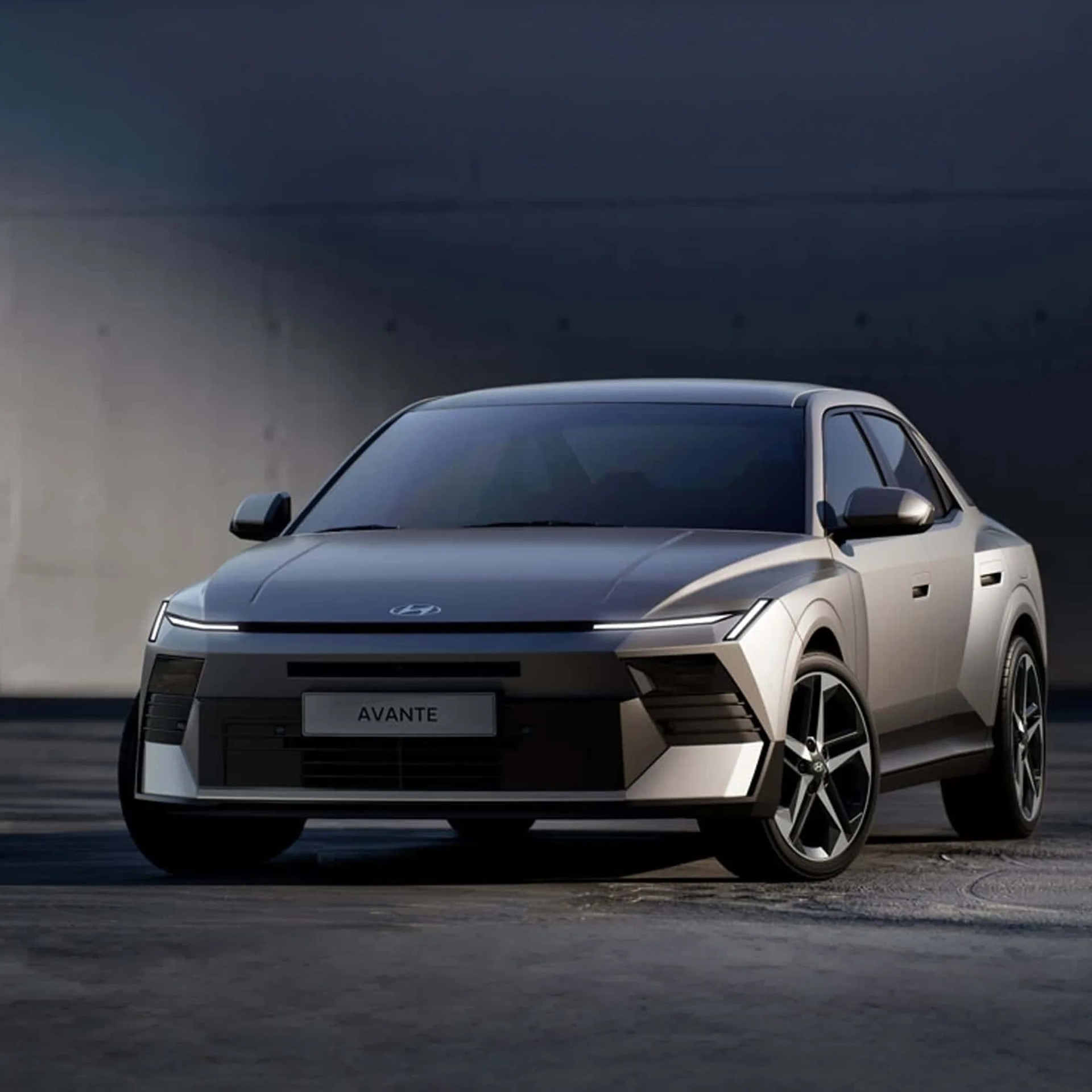 Silver Hyundai Avante car front view with sleek LED headlights and black grille on dark background.