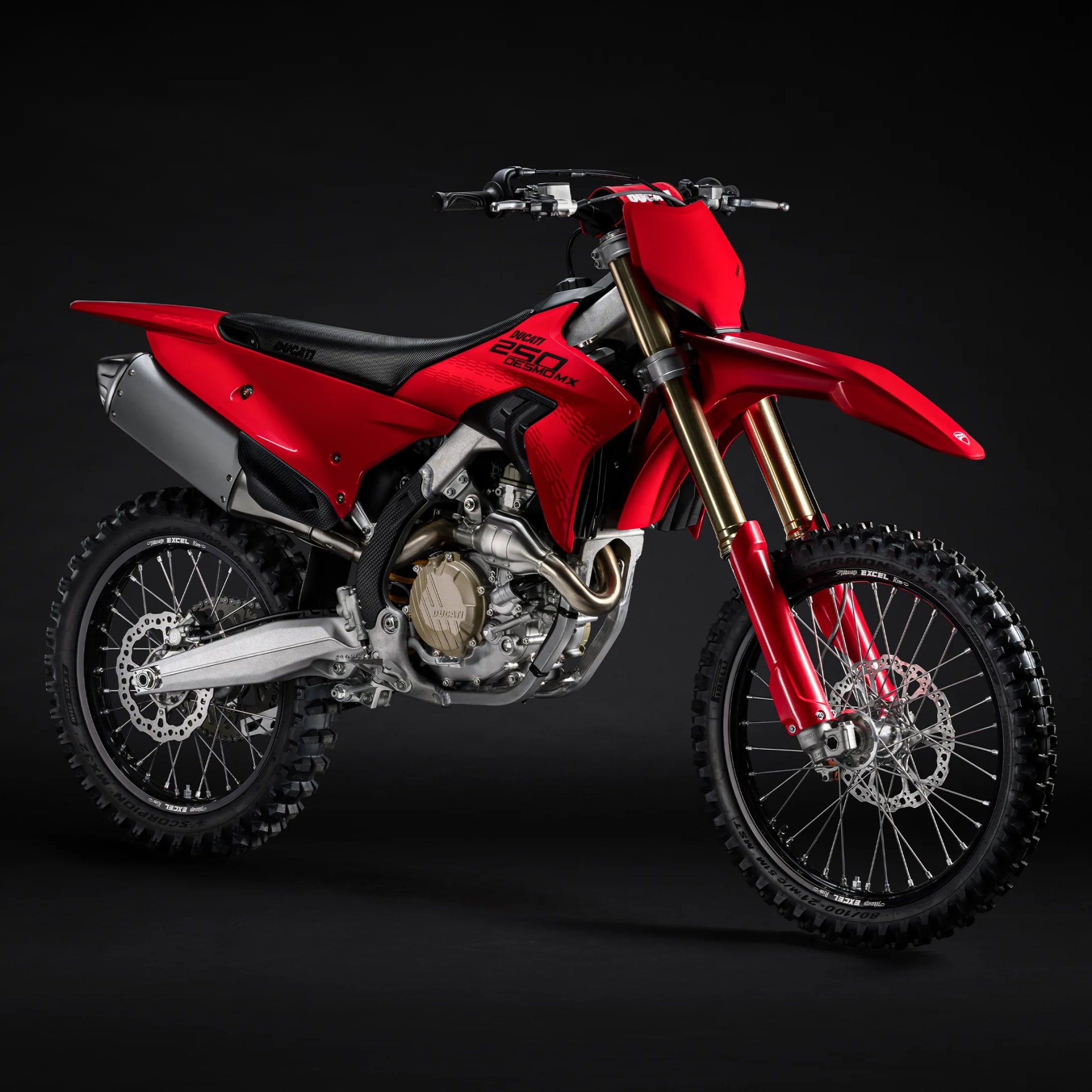 Red Ducati 250 Desmo MX dirt bike with black seat and gold front forks on black background.