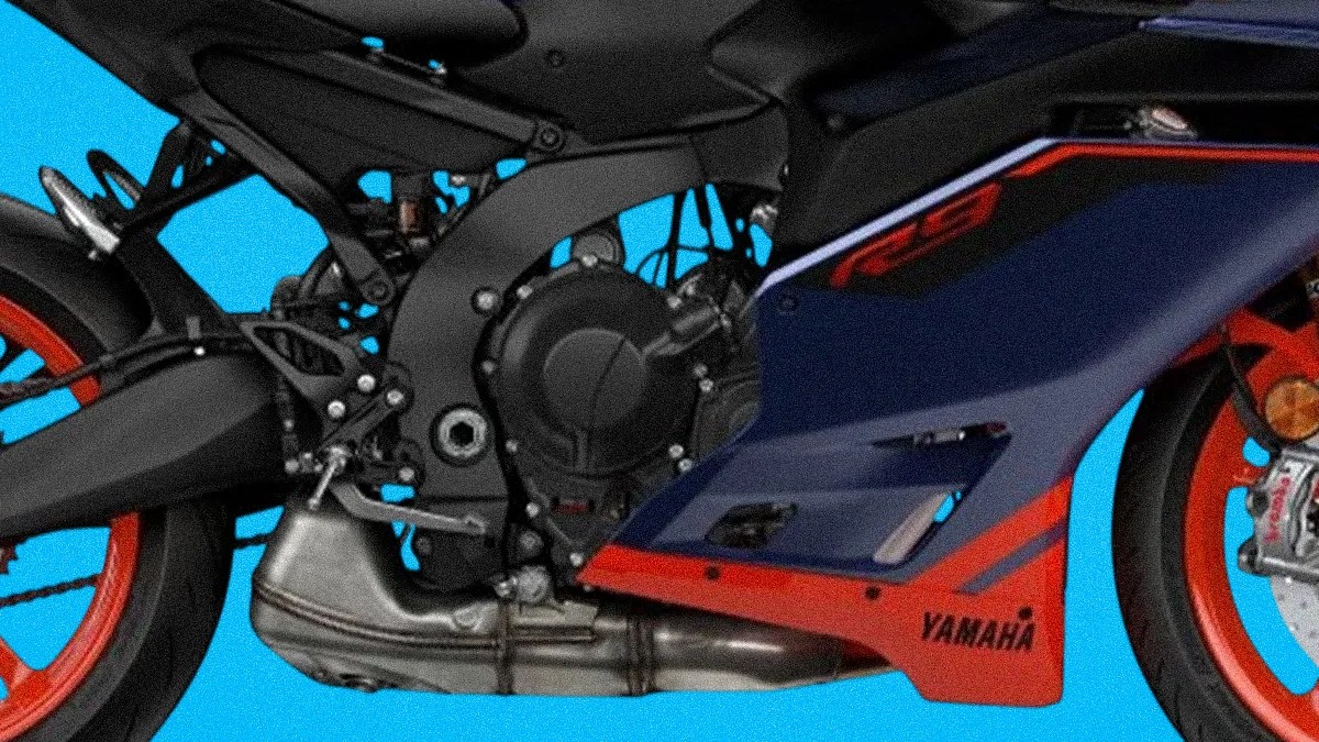 Close-up of a Yamaha motorcycle engine and exhaust with blue and red fairing and red wheels.