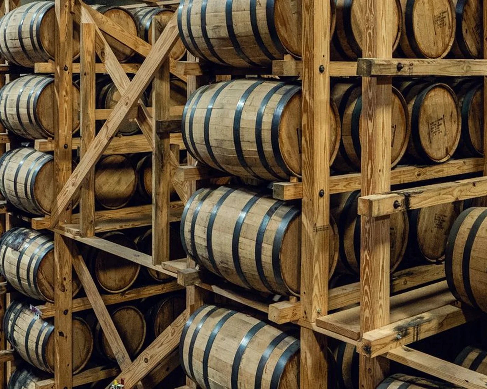 Wooden barrels stacked horizontally on wooden racks in a storage area.