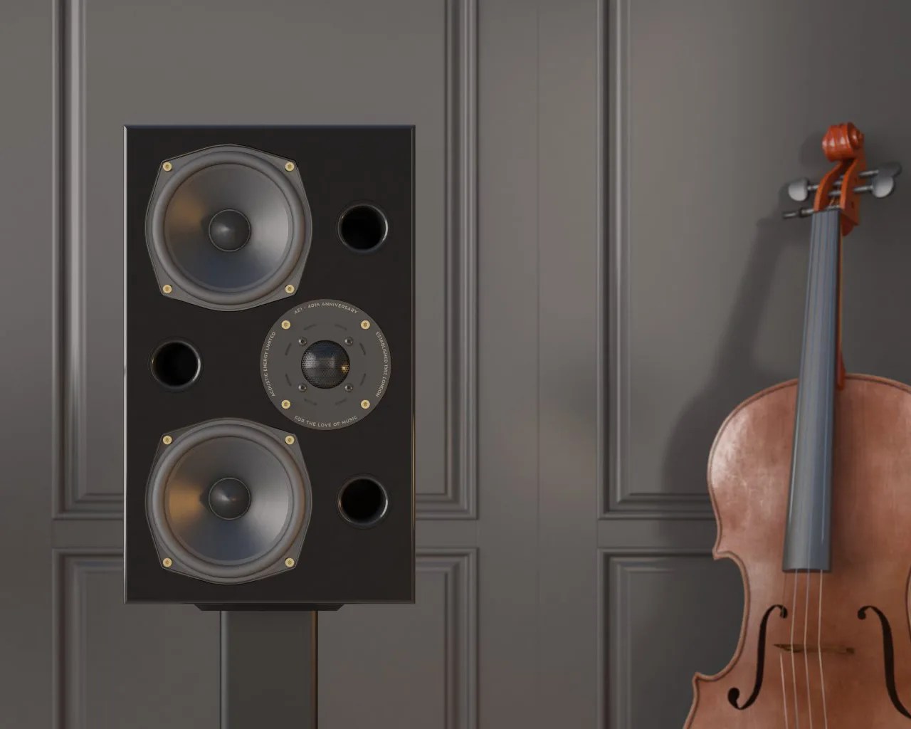 Black rectangular speaker with two large drivers and a central tweeter on a stand next to a brown cello against a gray paneled wall.