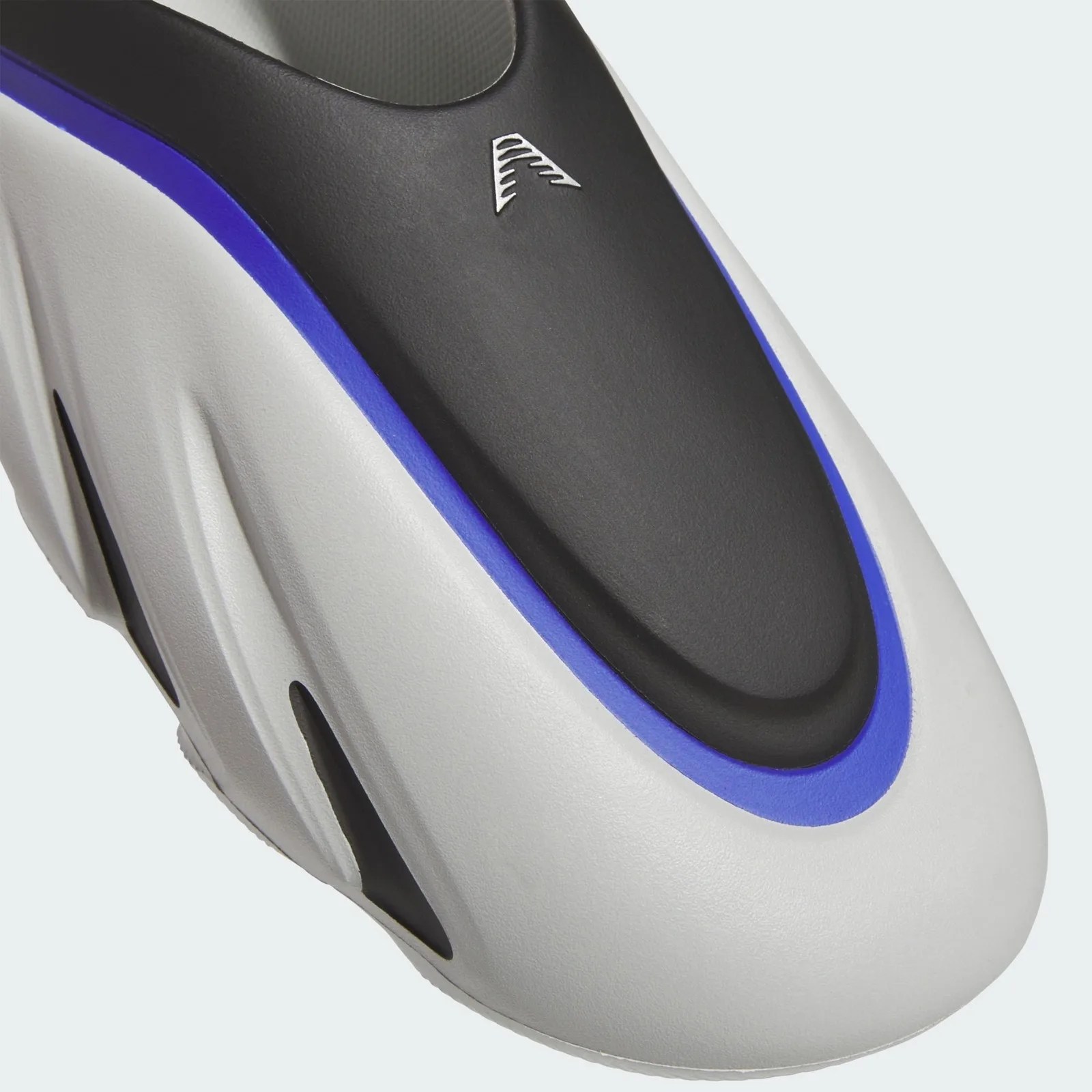 Close-up of a white sneaker toe with black and blue accents and a small silver logo on the black section.
