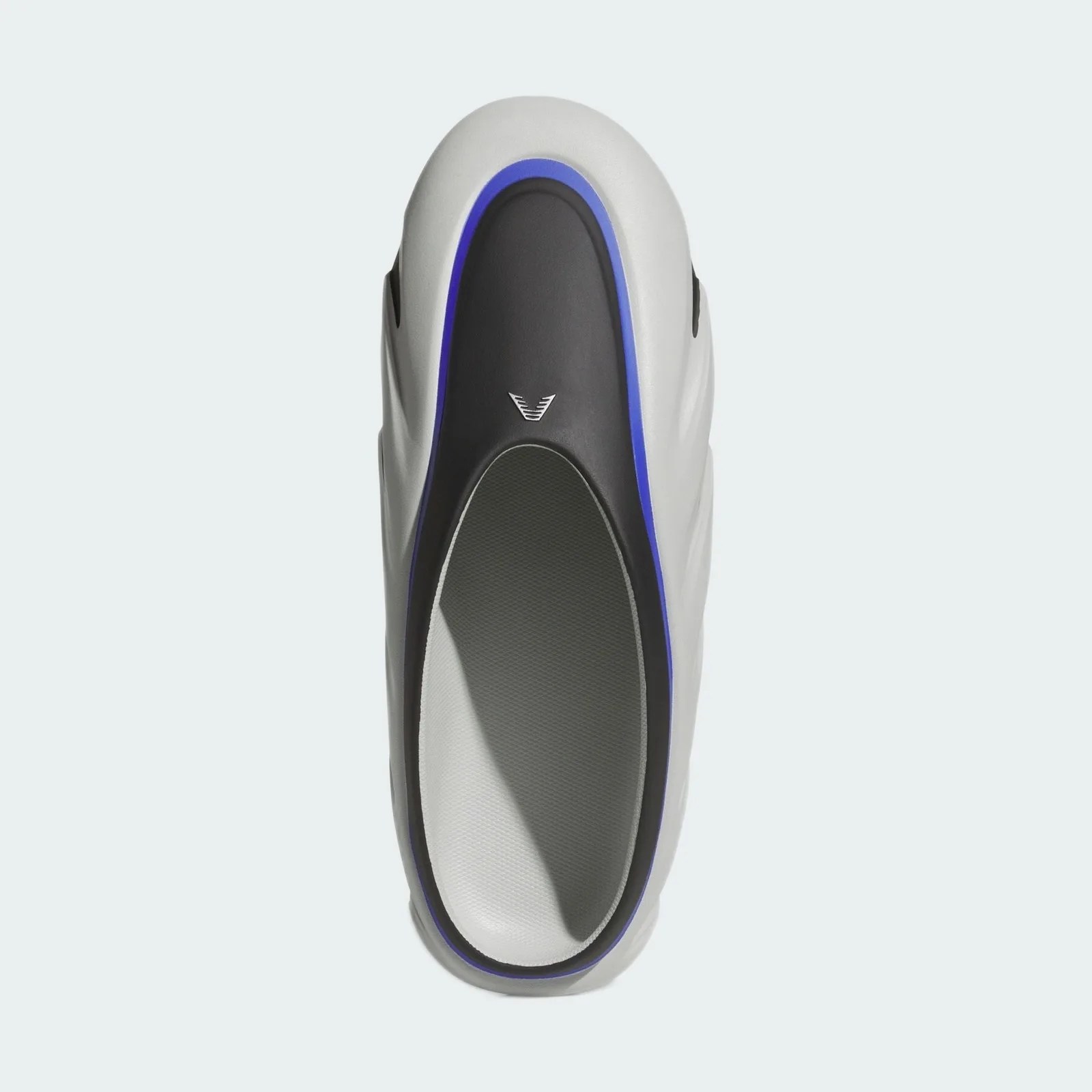 Top view of a white and black slip-on shoe with a blue trim and a small logo near the toe area.