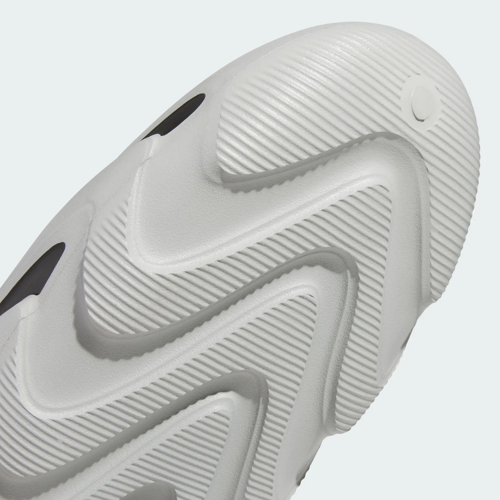 Close-up of a white textured shoe sole with wavy grooves and small black oval details.