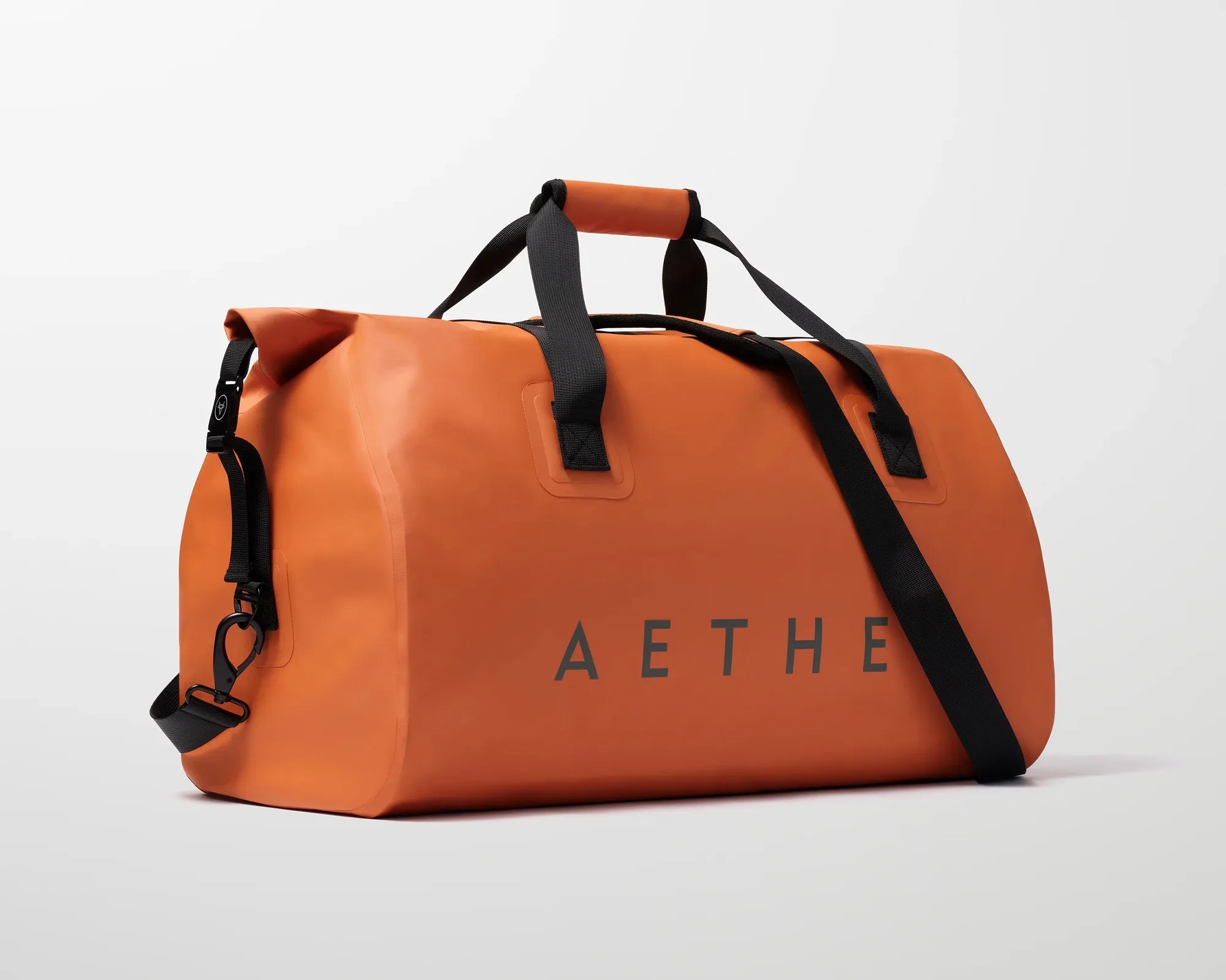 Orange waterproof duffel bag with black straps and "AETHE" printed on the side.