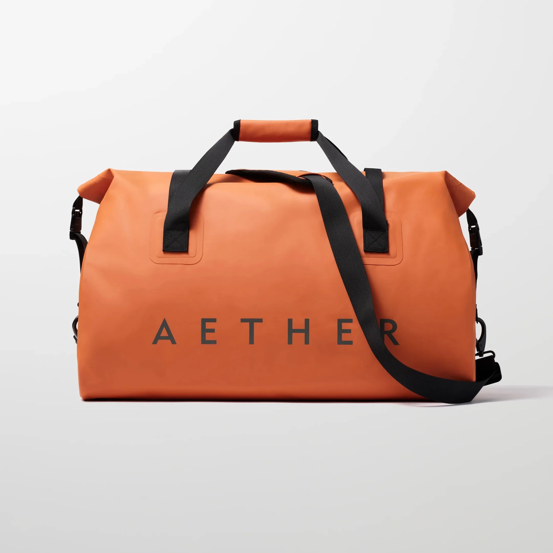 Orange roll-top duffel bag with black handles and shoulder strap, featuring "AETHER" text.