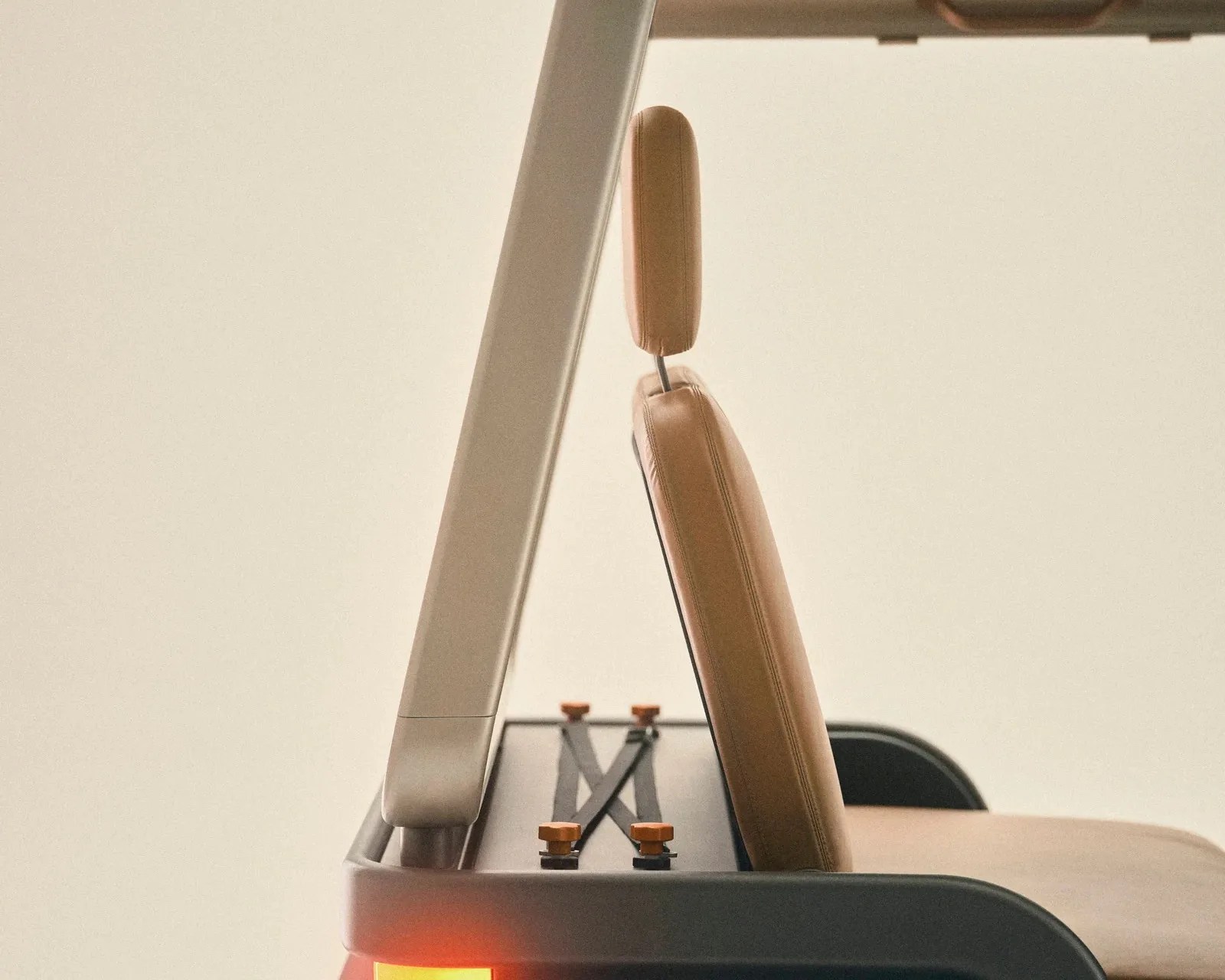 Tan leather car seat with headrest and beige roll bar visible inside a vehicle.
