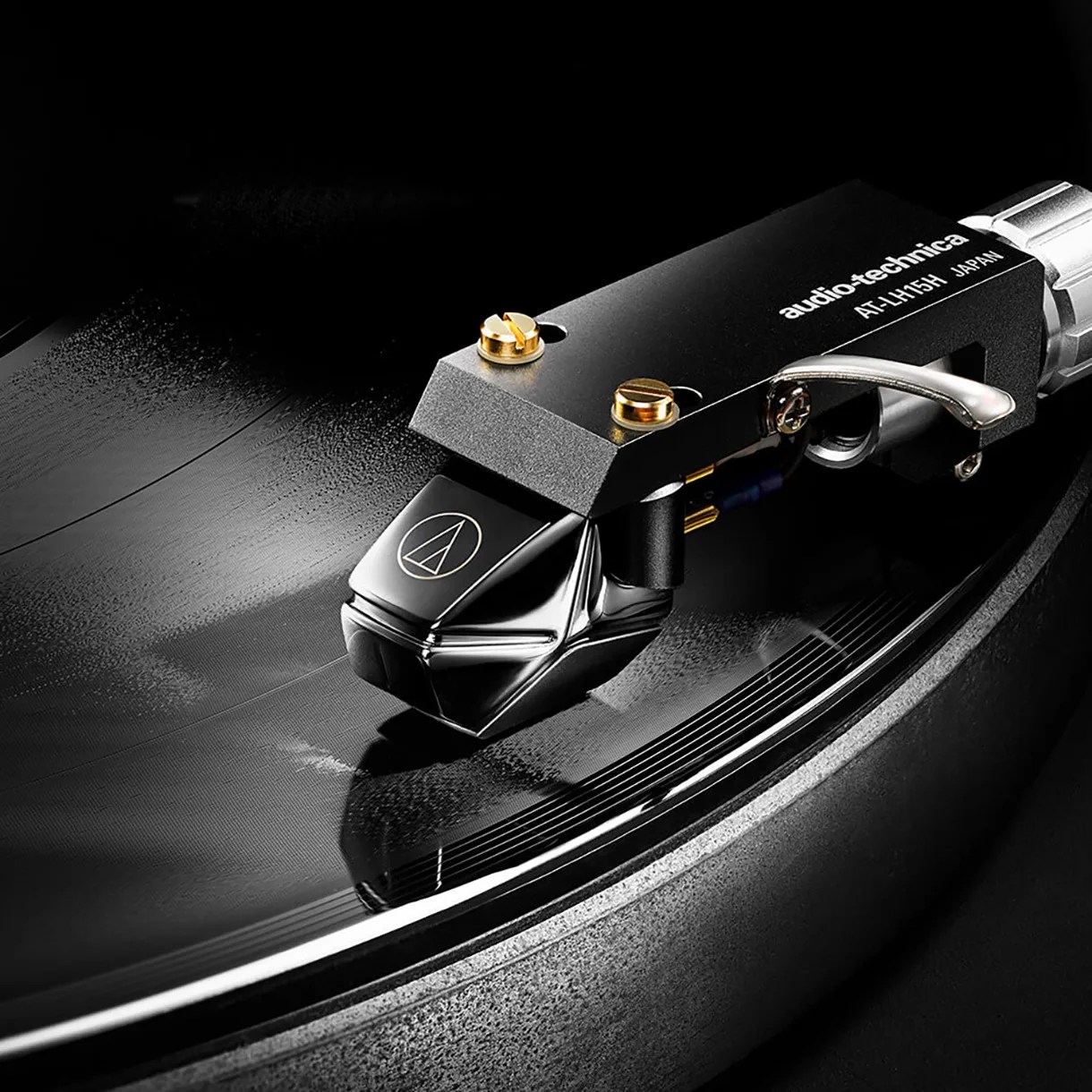 Close-up of an Audio-Technica AT-LH15H cartridge mounted on a turntable tonearm over a vinyl record.