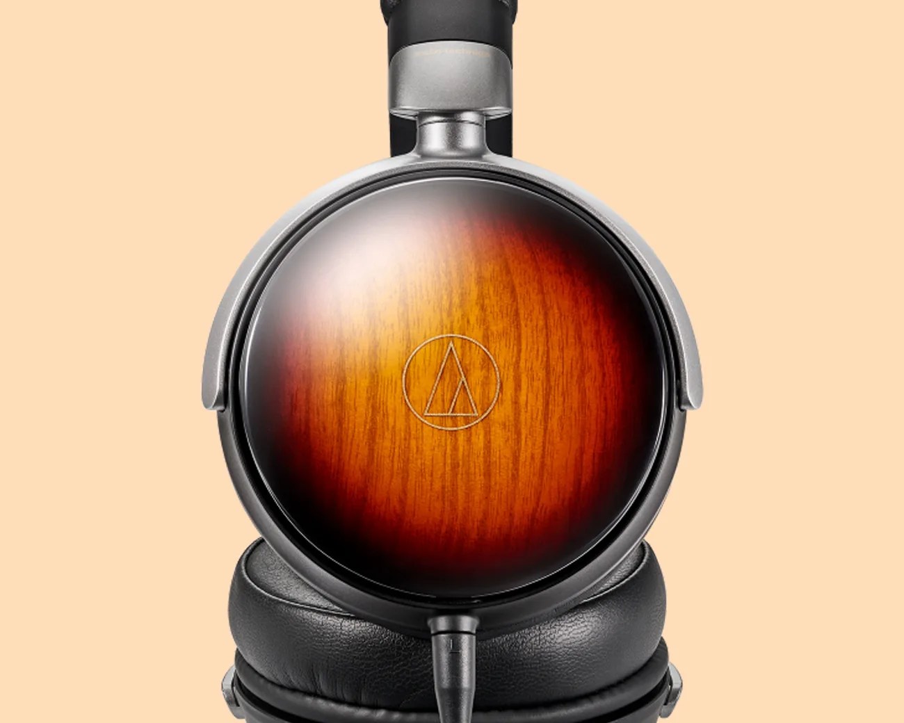 Over-ear headphone with wooden ear cup featuring a sunburst finish and black leather ear cushion.