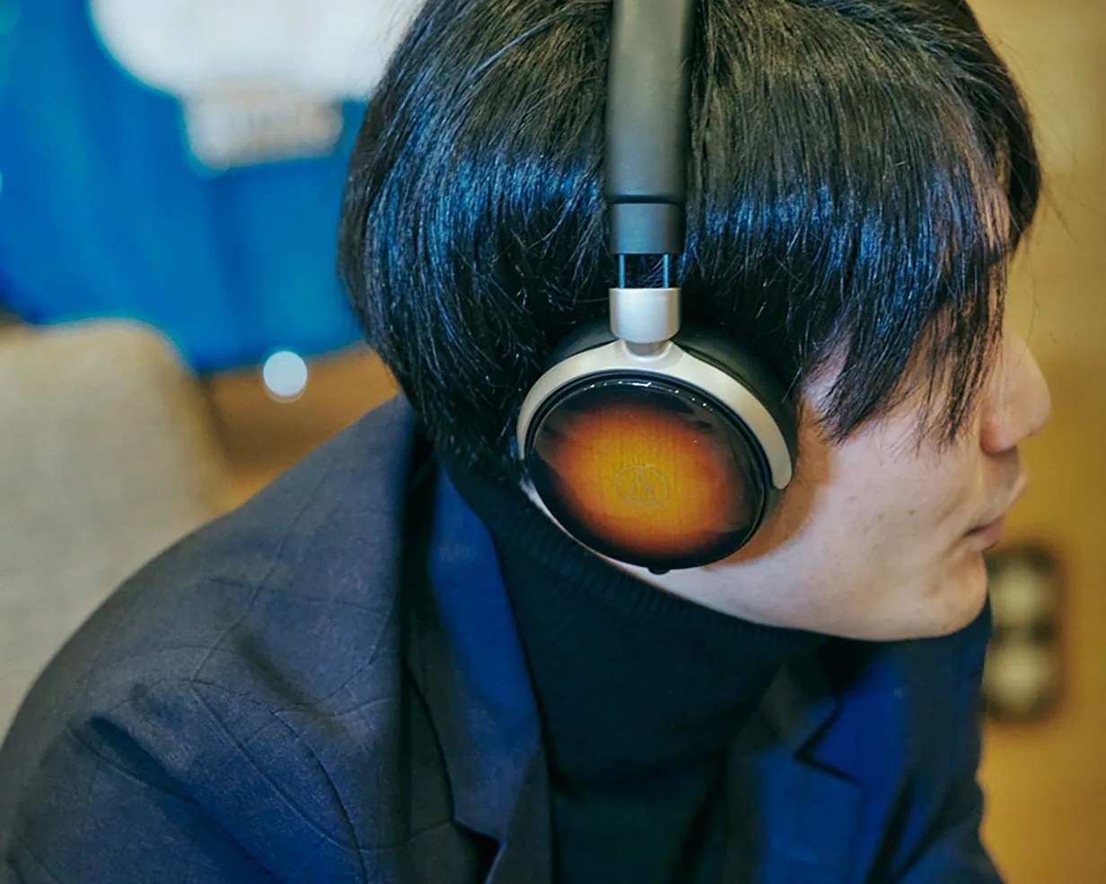 Person wearing over-ear headphones with wood-finish ear cups and black headband.